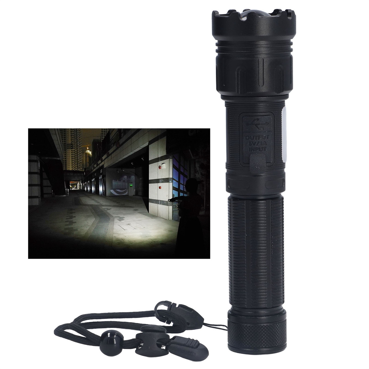 Schwarze Taschenlampe mit Lanyard, leuchtet in dunkler, urbaner Umgebung.