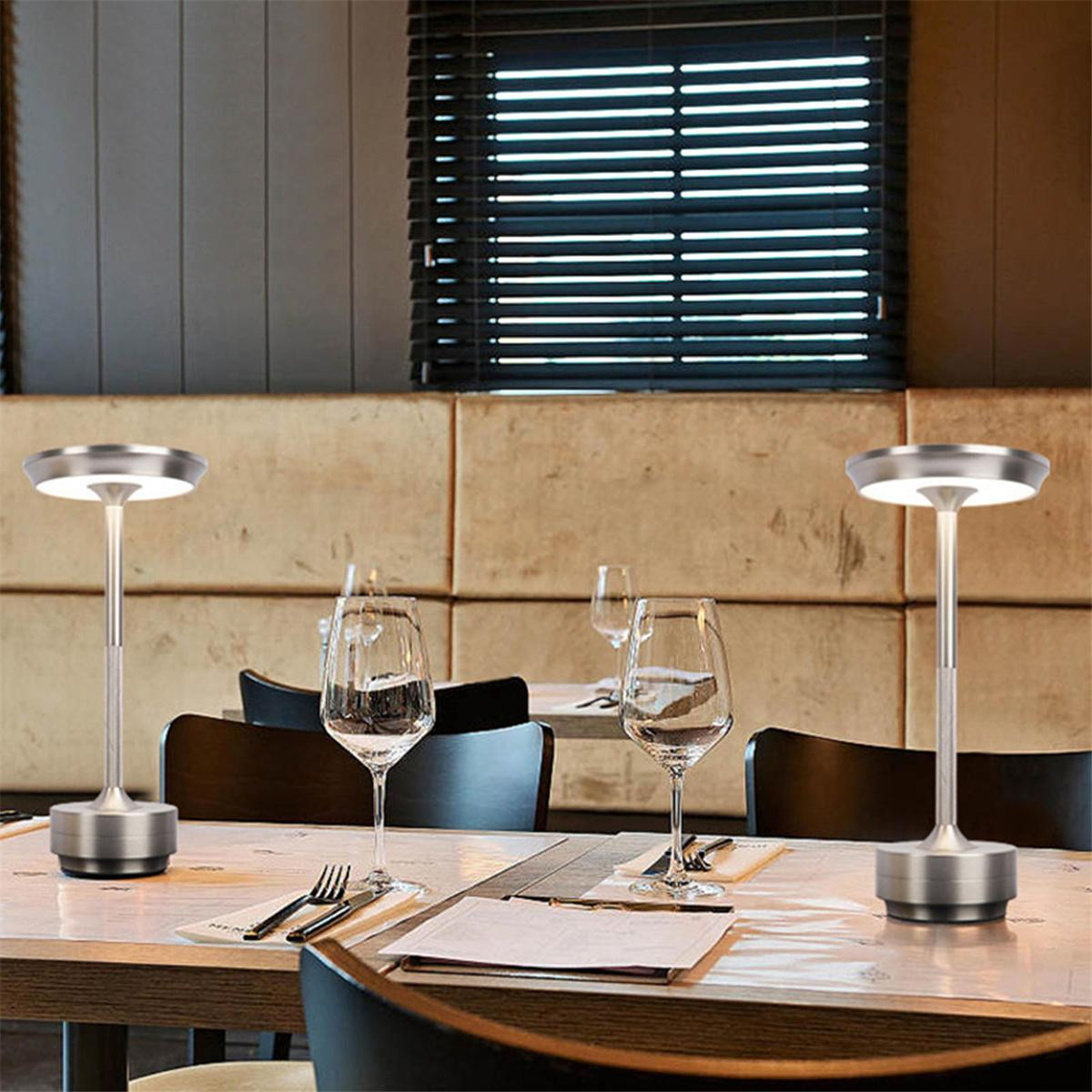 Zwei silberne Tischlampen in einem Restaurant, einschließlich Gläser und Tisch.