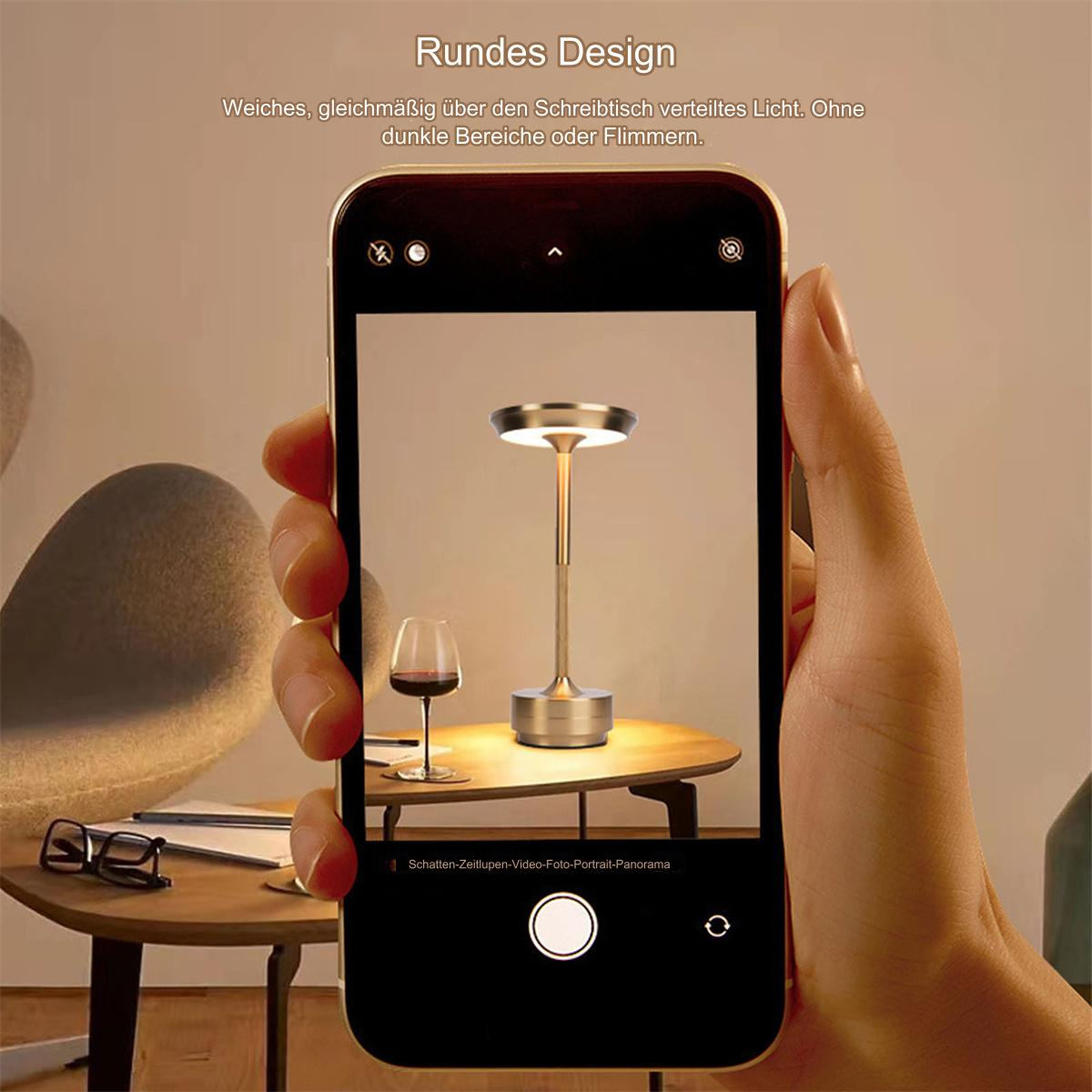 Eine Hand, die ein Telefon hält, das ein Foto einer Lampe und eines Weinglases aufnimmt.