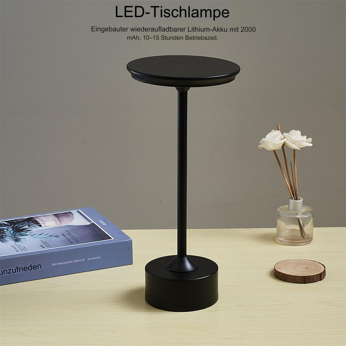 Schwarze LED-Tischlampe mit rundem Aufsatz, auf einem Holztisch mit Dekoration.