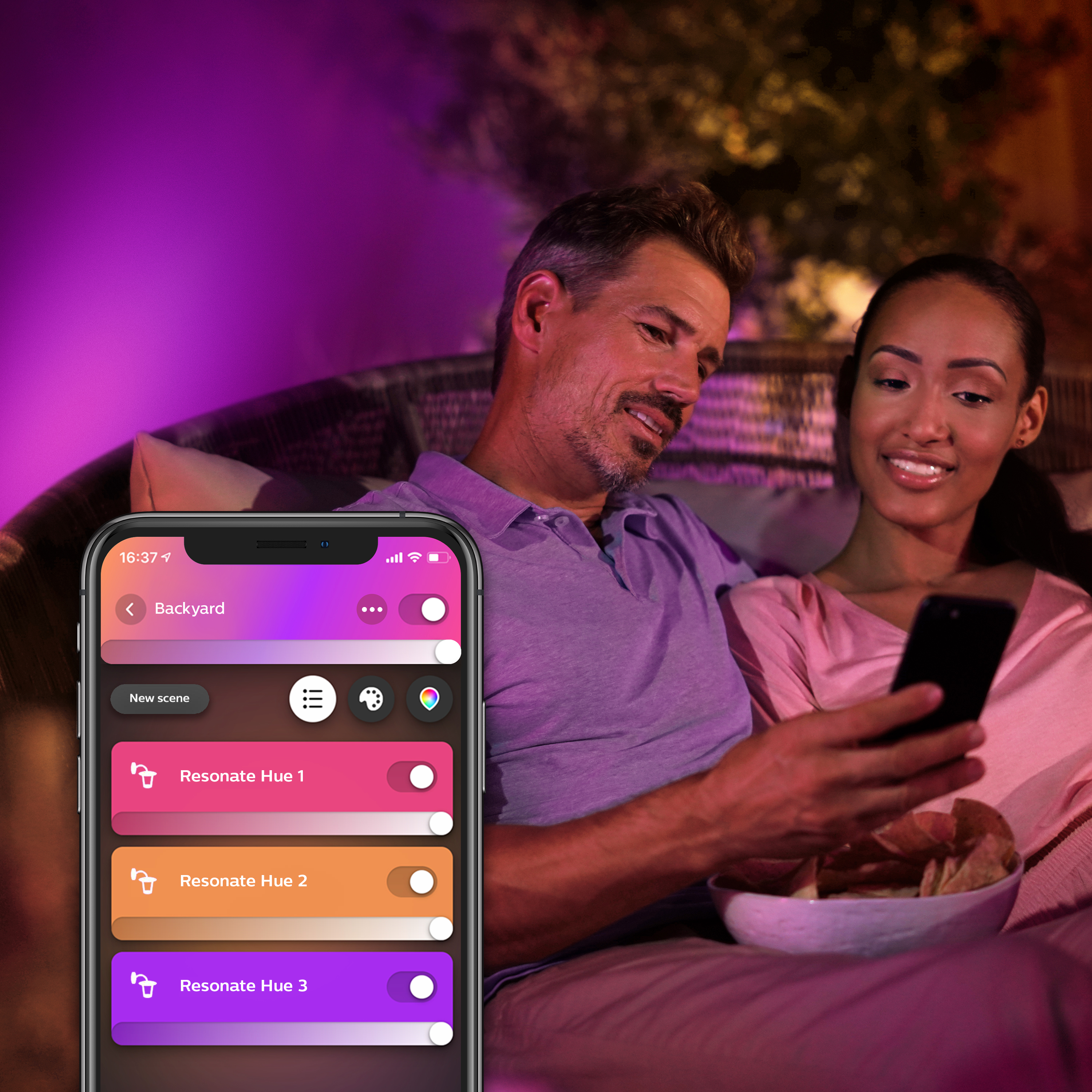 Een stel gebruikt een telefoon met een smart home app. Paars omgevingslicht.