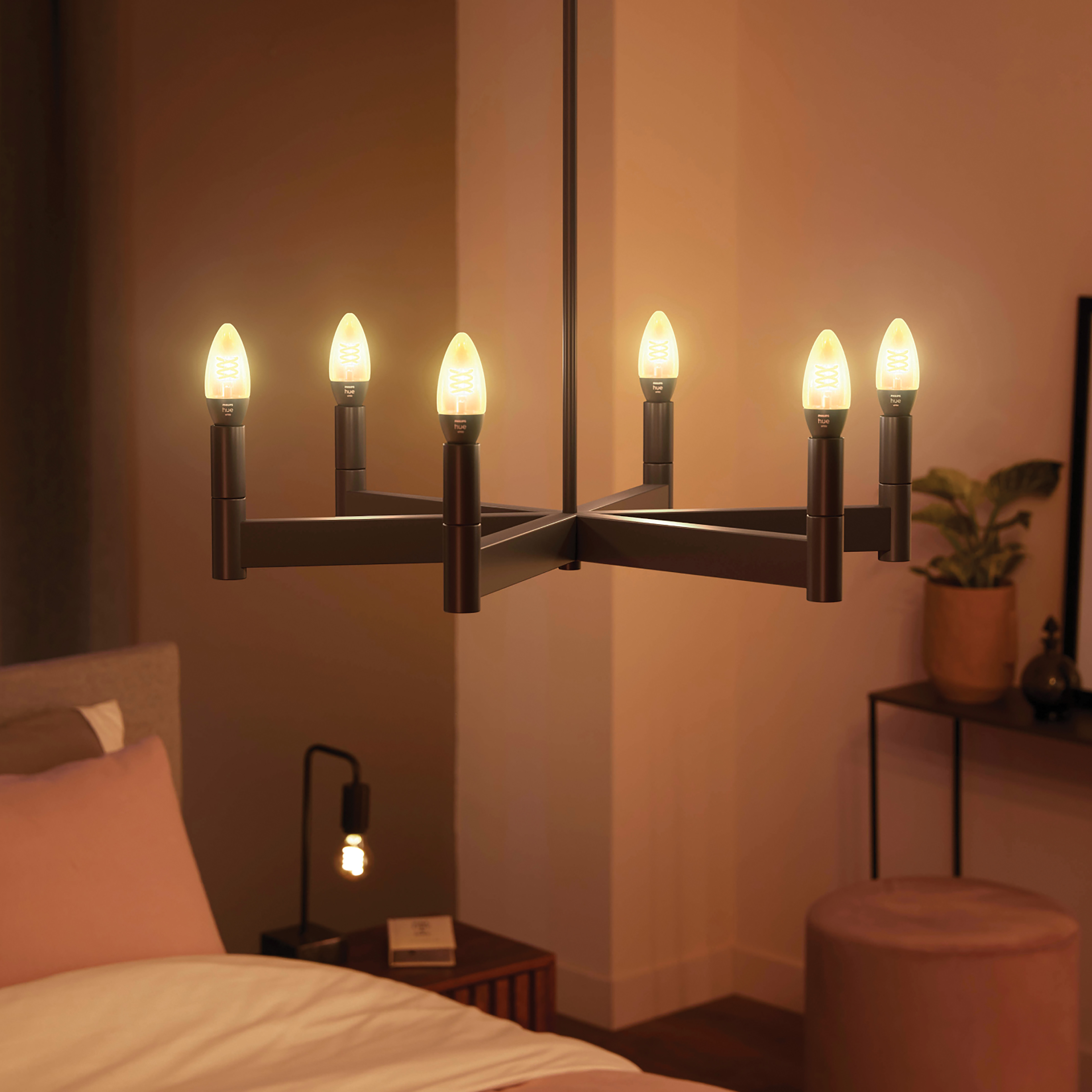 Żyrandol z sześcioma światłami w kształcie świec, ciemną ramą, ciepłym światłem.