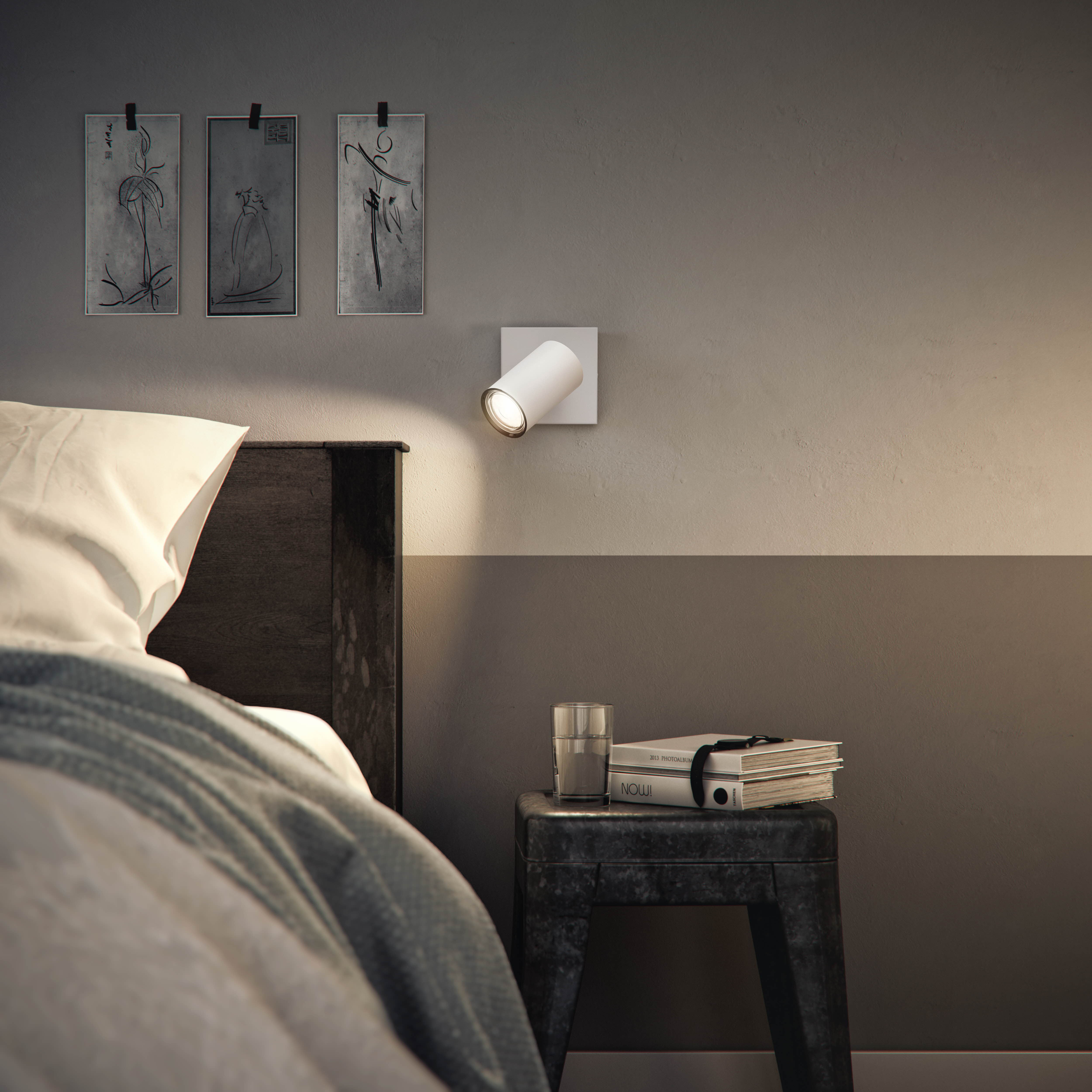 Schlafzimmer: Bett, Nachttisch mit Lampe, Kunst an der Wand. Grau-Weiß-Farbschema.