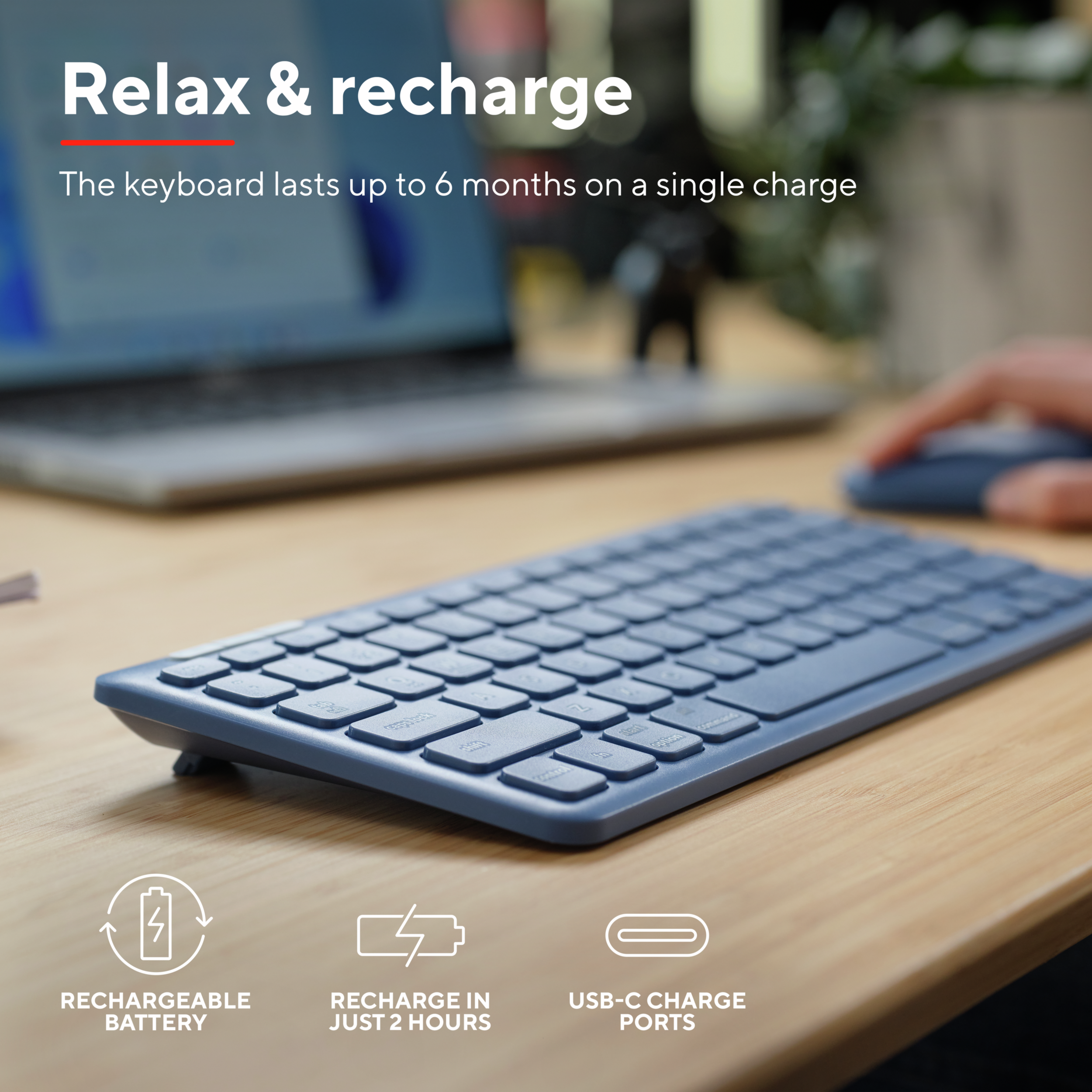 Niebieska klawiatura na drewnianym biurku, z ikonami ładowania, portów i akumulatora.