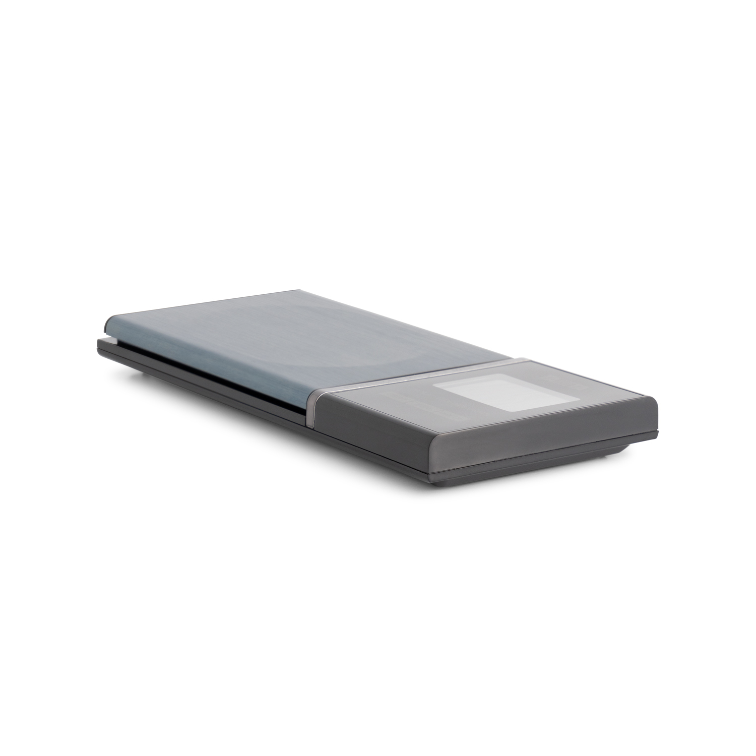 A gray rectangular device lies on a white surface, it is a scale or a digital display.