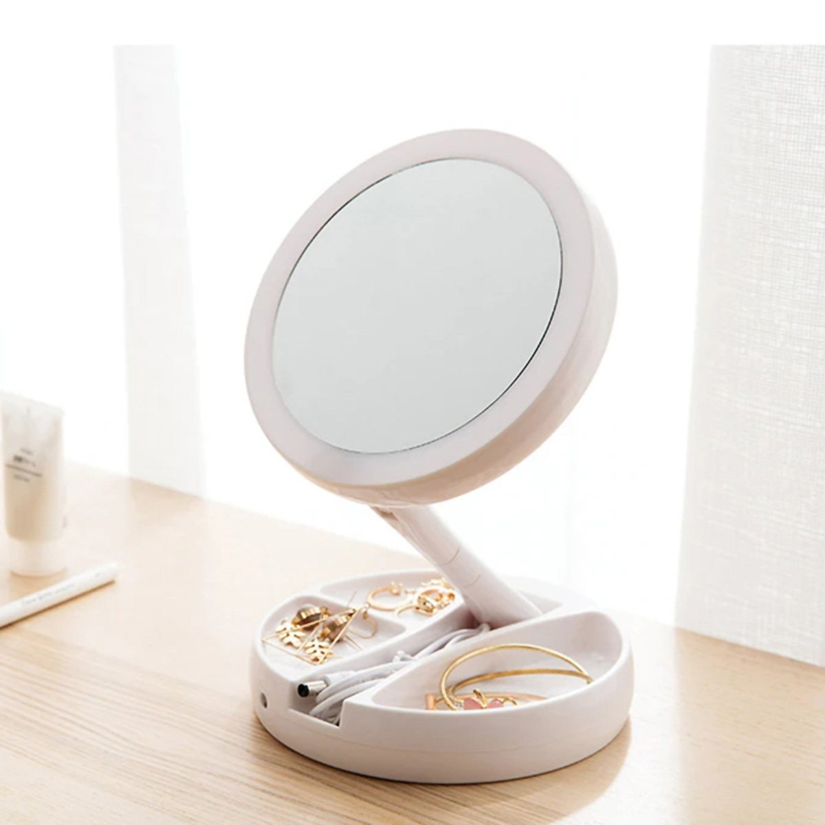 Espejo de tocador blanco y plegable con joyas y cosméticos en superficie de madera.