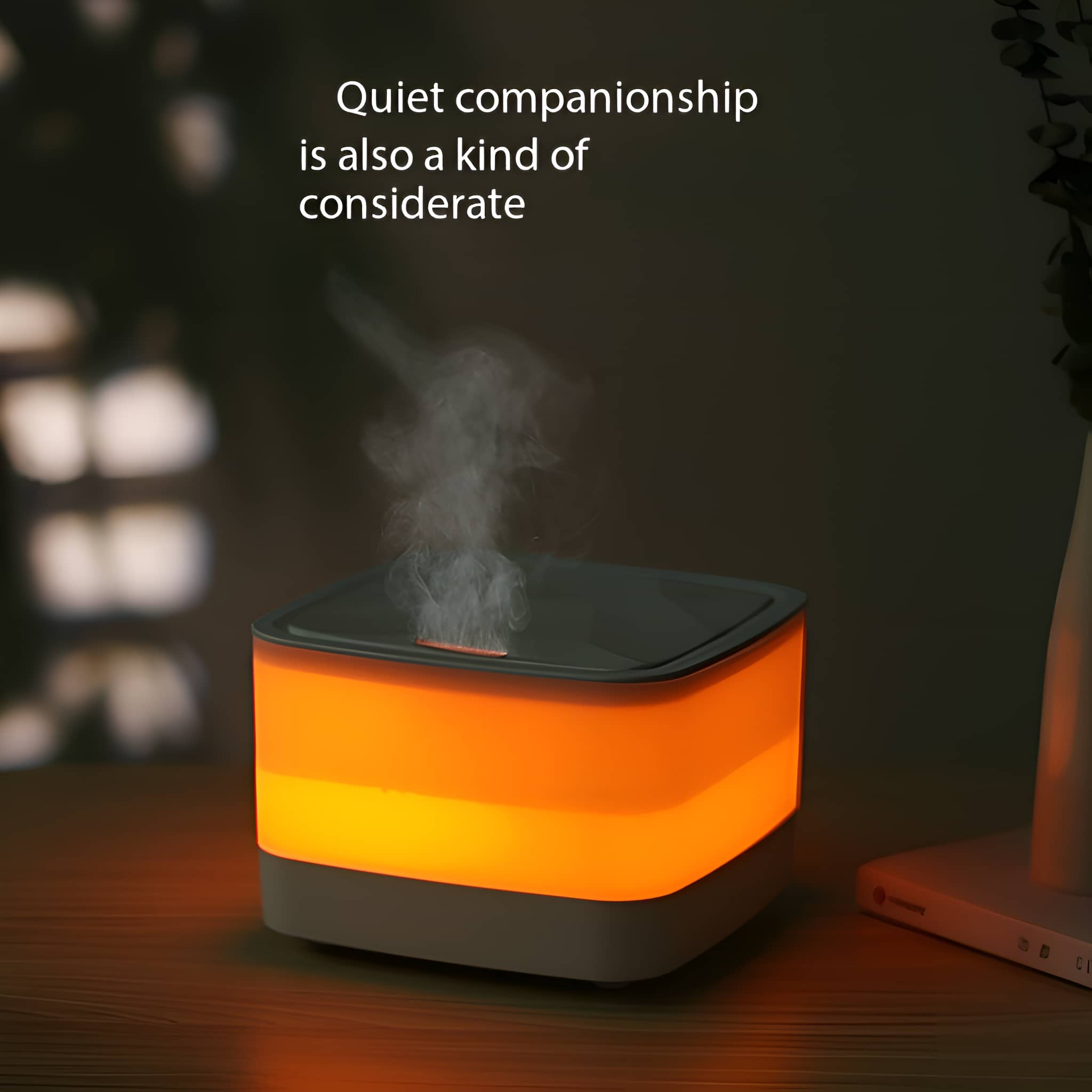Weiß-grauer Luftbefeuchter. Orangenes Licht emittiert, mit dunklem Hintergrund und Buch auf dem Tisch.