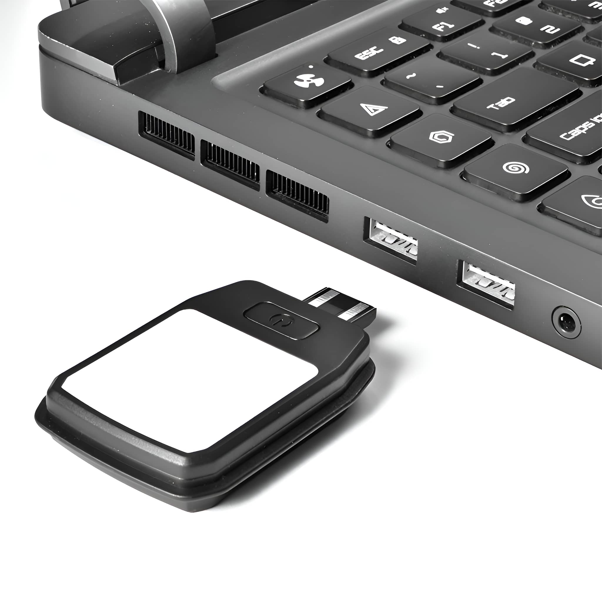 Ein schwarzes quadratisches Gerät ist an den USB-Anschluss eines Laptops angeschlossen. Ein weißer Bereich ist darauf.