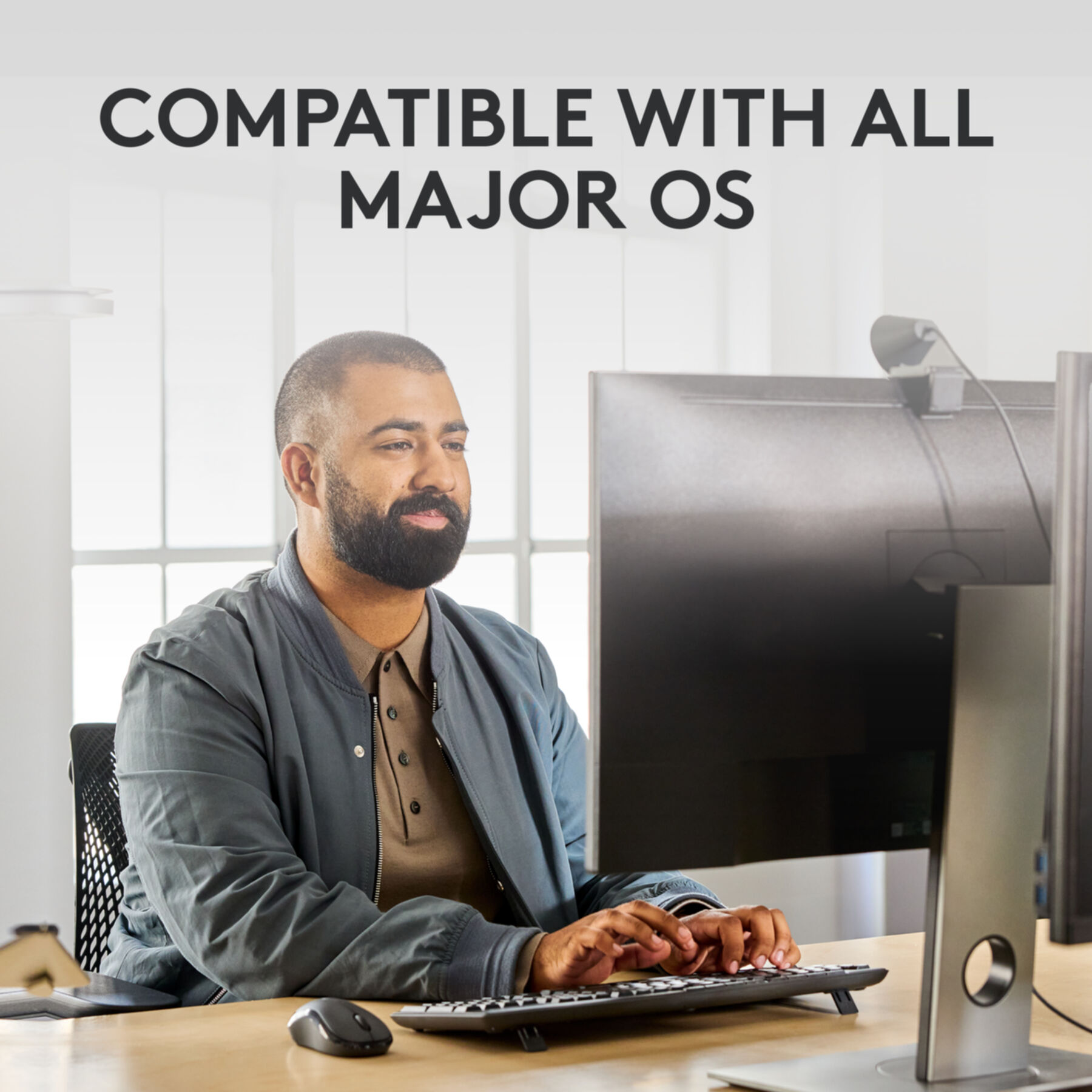 Mężczyzna używający klawiatury, monitor za nim. Tekst "COMPATIBLE WITH ALL MAJOR OS" u góry.