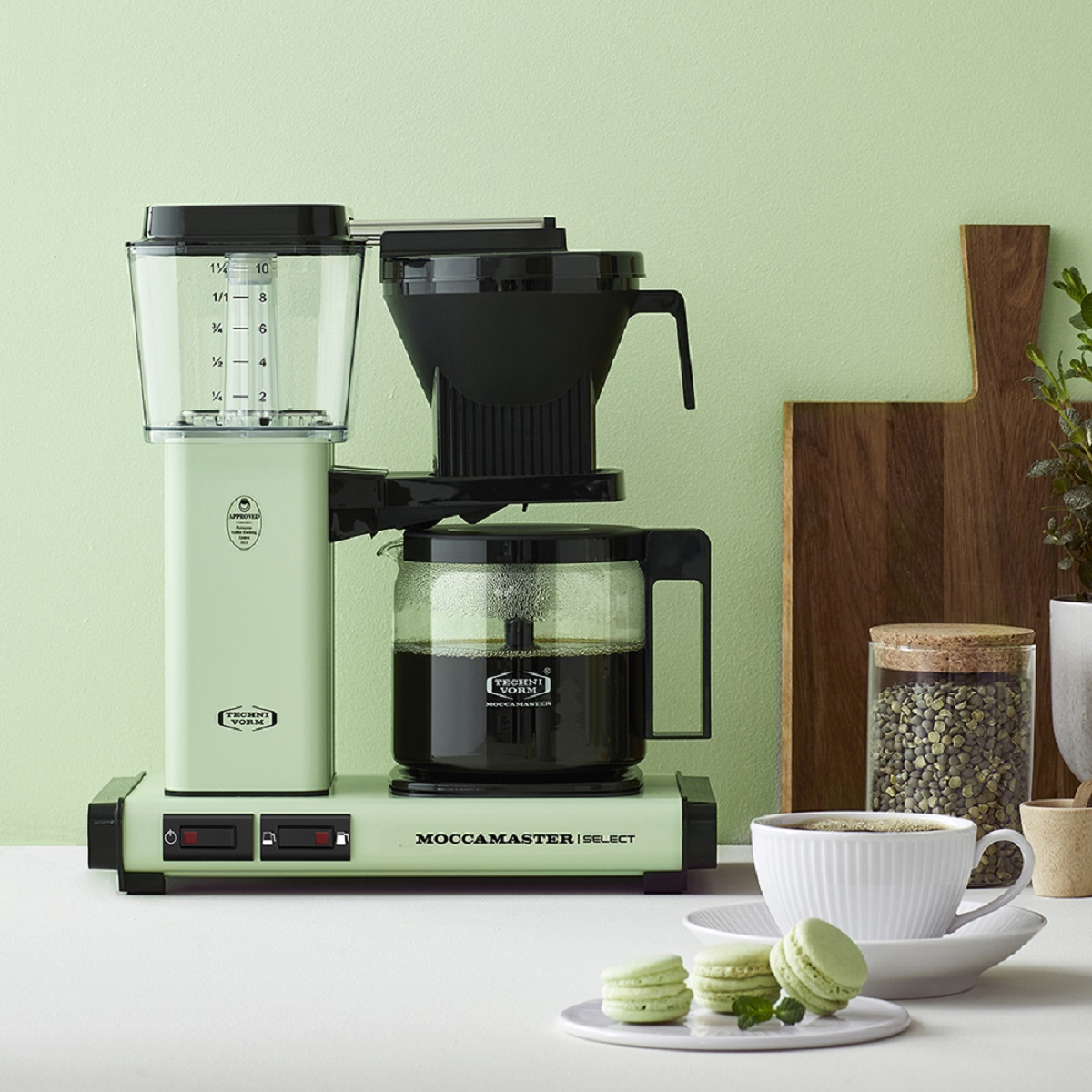Green and black coffee machine with a glass carafe filled with coffee.