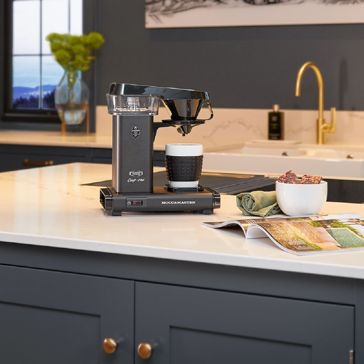Coffee machine on a white countertop with a mug.
