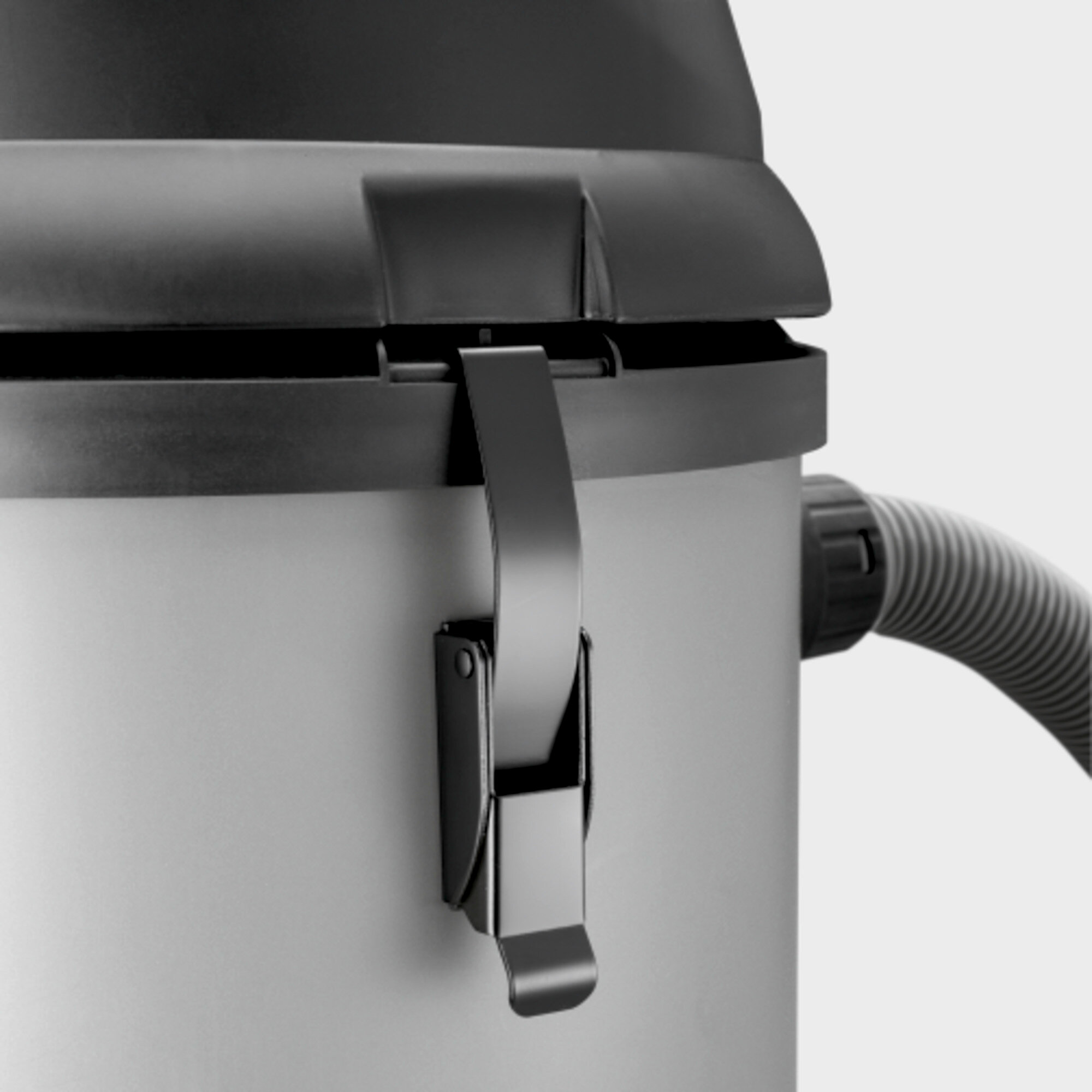 Un aspirateur avec un couvercle noir et un loquet métallique.