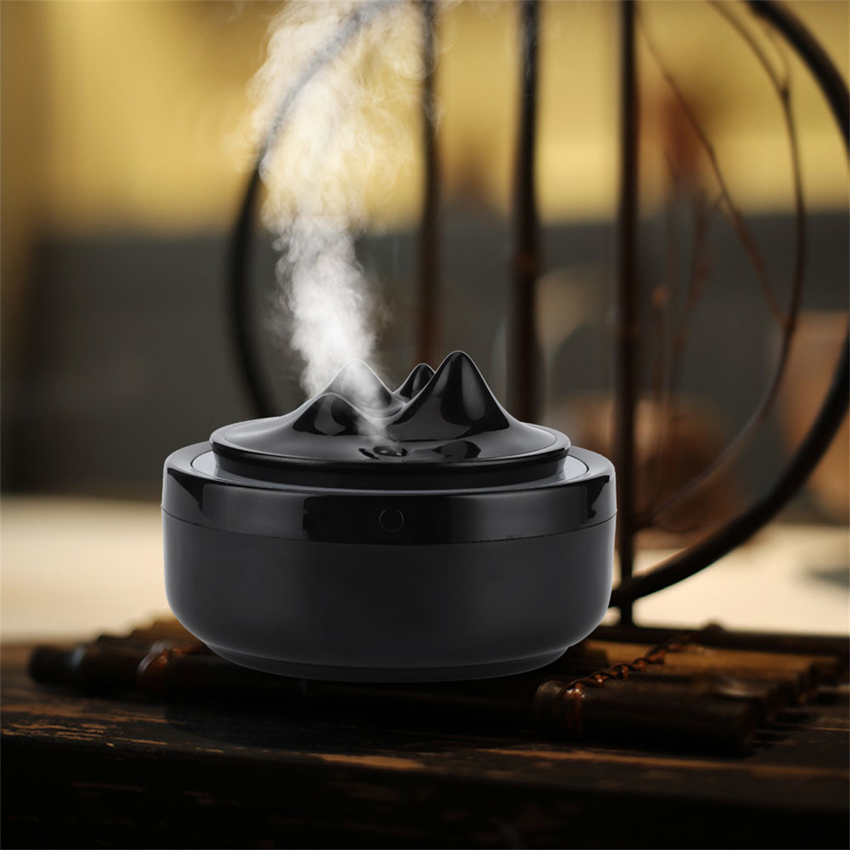Schwarzer Diffusor für ätherische Öle mit bergförmigem Oberteil und Dampfausstoß.