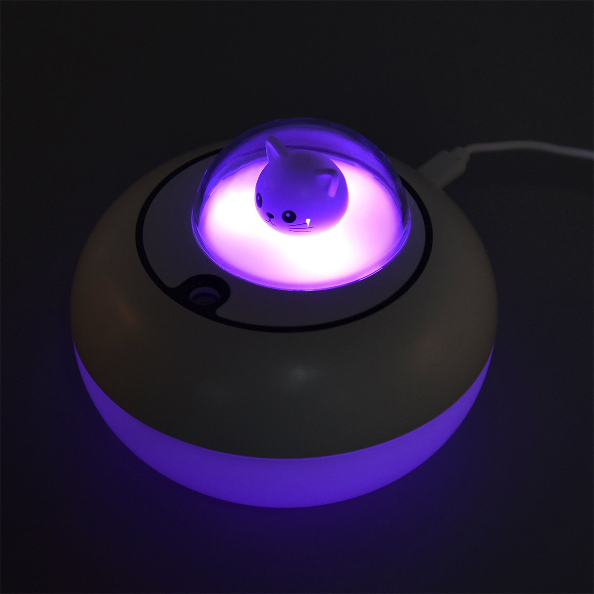 Eine Lampe mit einer Katzenfigur im Inneren, beleuchtet mit lila Licht, auf einer weißen Oberfläche.