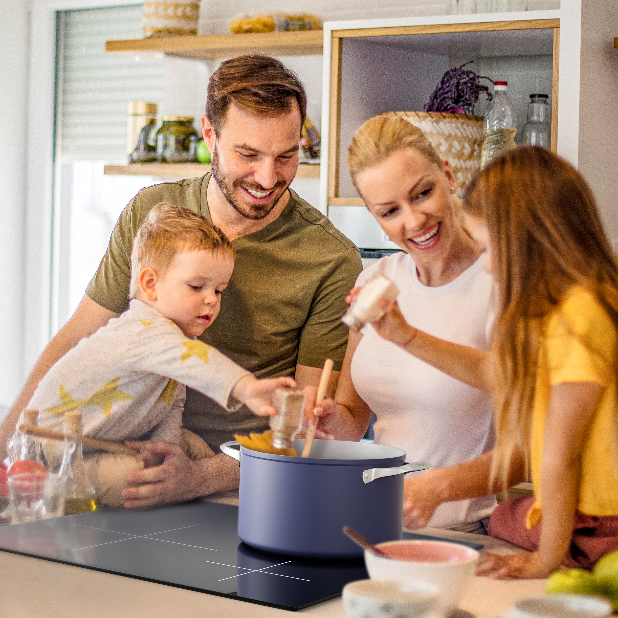 Famille cuisinant dans une cuisine; parents et enfants autour d'une casserole.