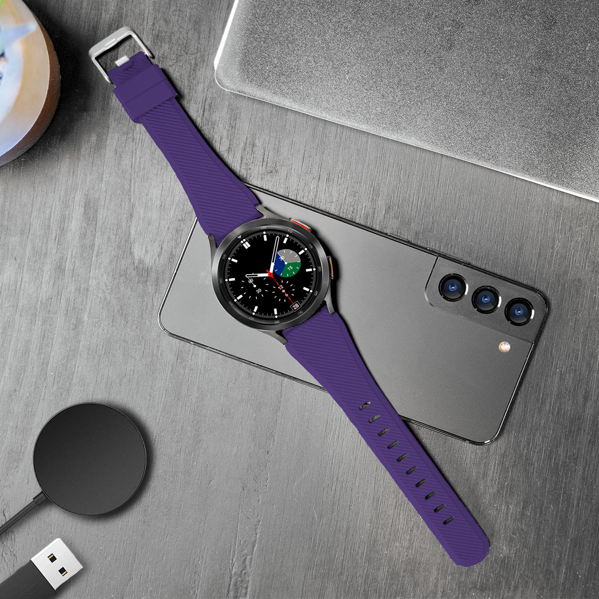 Eine lila Uhr mit schwarzem Zifferblatt und ein Smartphone daneben.