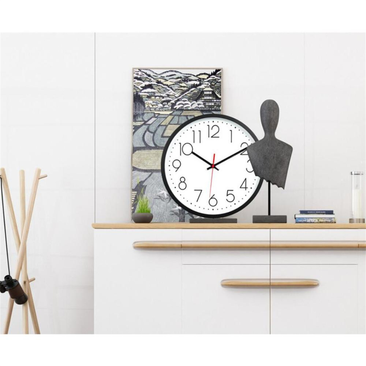 Ein weiß getäfelter Raum mit Uhr, Kunstdruck, Skulptur und Garderobenständer. Ein Holzschrank steht in der Mitte.