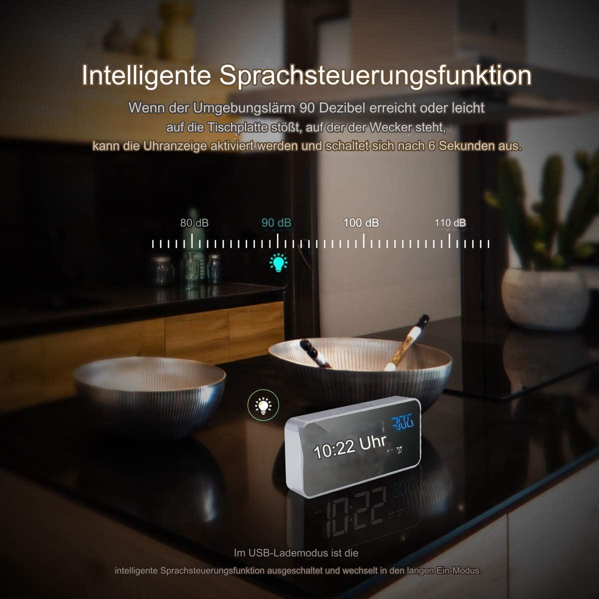 Eine schwarze Digitaluhr mit Glühbirnen-Symbol. Schalen und eine Arbeitsplatte im Hintergrund.