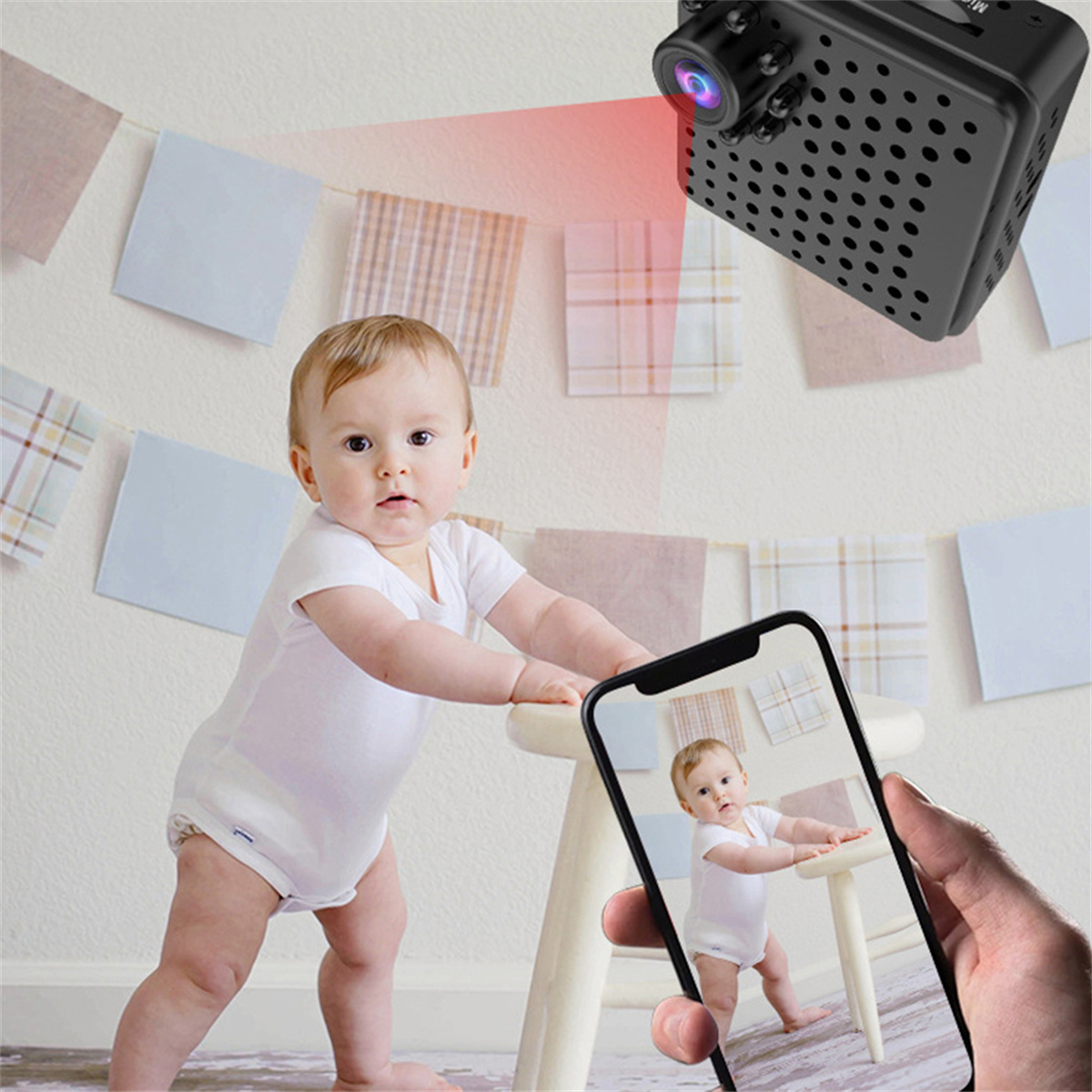 Ein Baby steht an einem kleinen Tisch, eine Kamera nimmt das Baby auf. Ein Telefon zeigt das Baby.