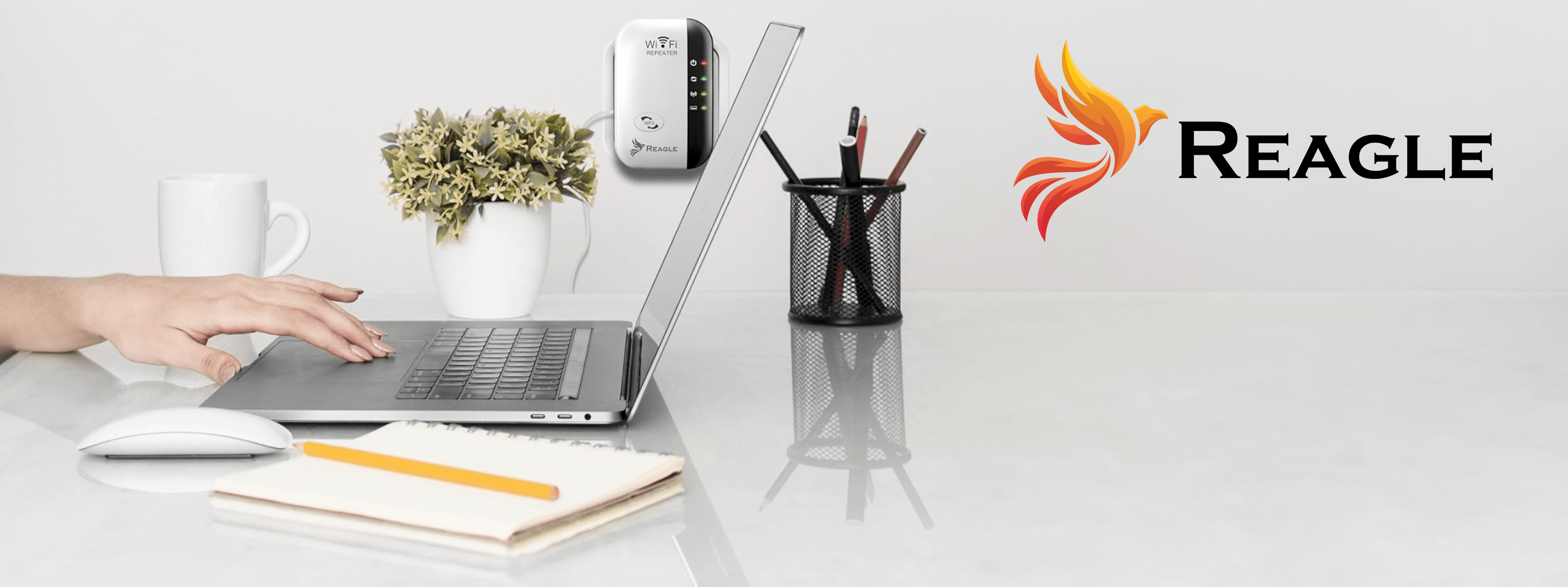 Osoba używająca laptopa z myszką i notatnikiem na białym biurku, obok artykułów biurowych.