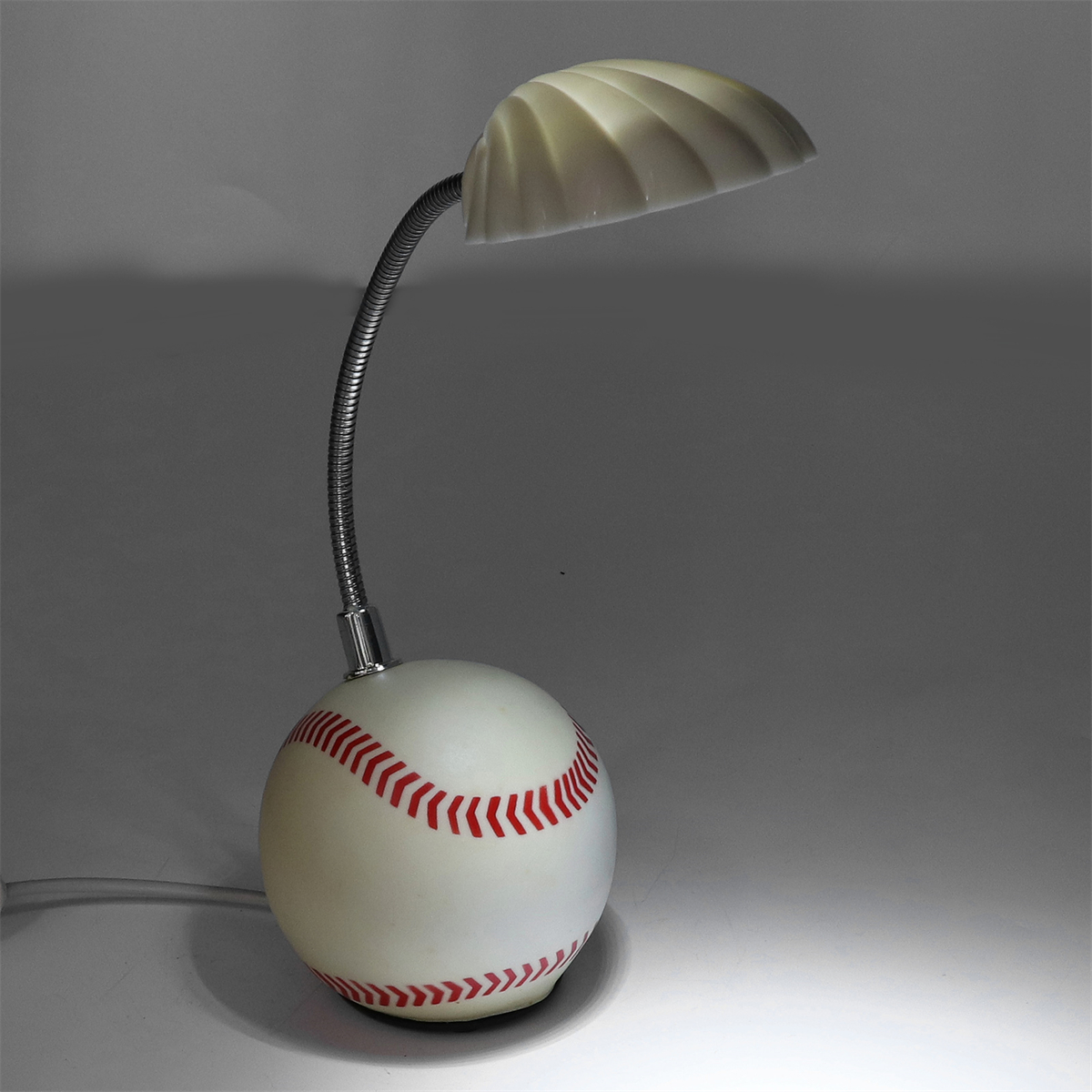 Eine baseballförmige Lampe mit flexiblem silbernen Hals und weißem Lampenschirm. Die Basis ist ein Baseball.