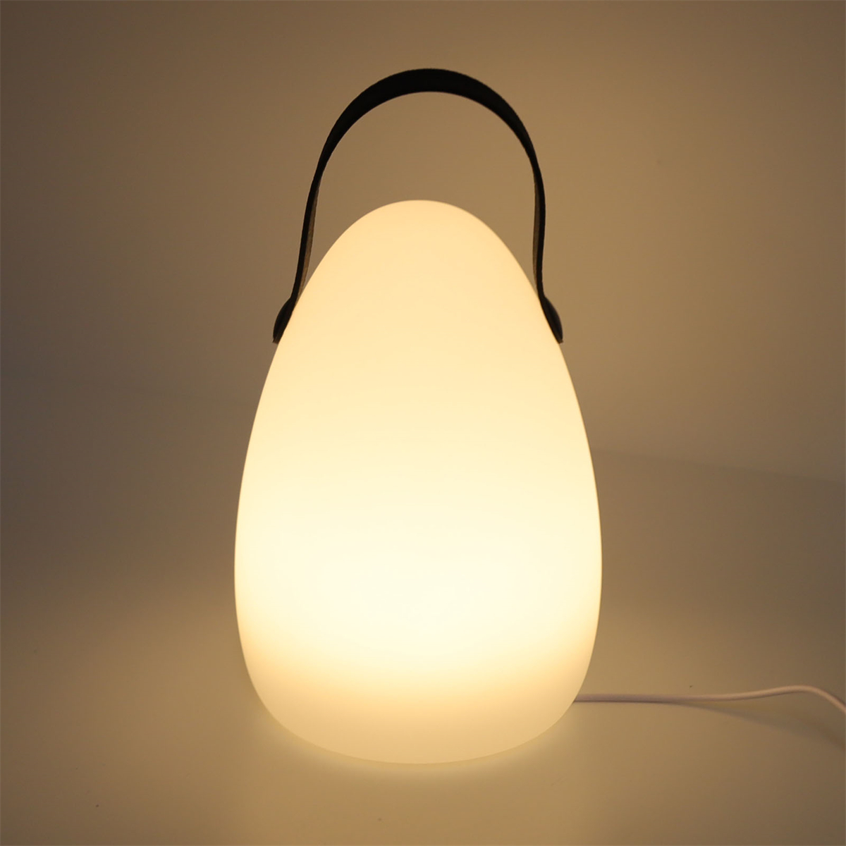 Eine weiße, eiförmige Lampe mit schwarzem Griff, die ein warmes Leuchten wirft.