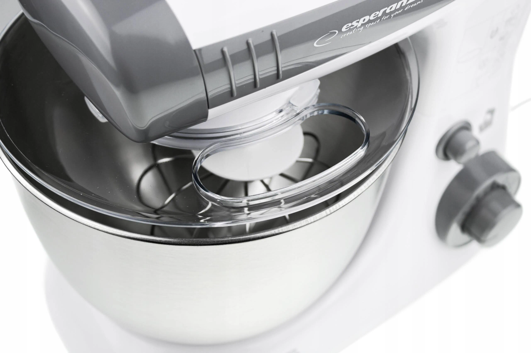 Primer plano de una batidora de cocina blanca con bol de acero inoxidable y protector antisalpicaduras transparente.