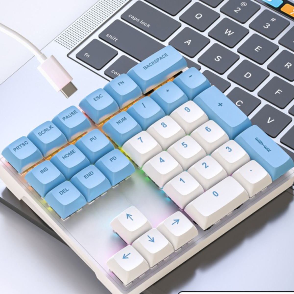 Nahaufnahme einer weißen und blauen Tastatur mit farbigen Tasten und USB-C-Kabel.