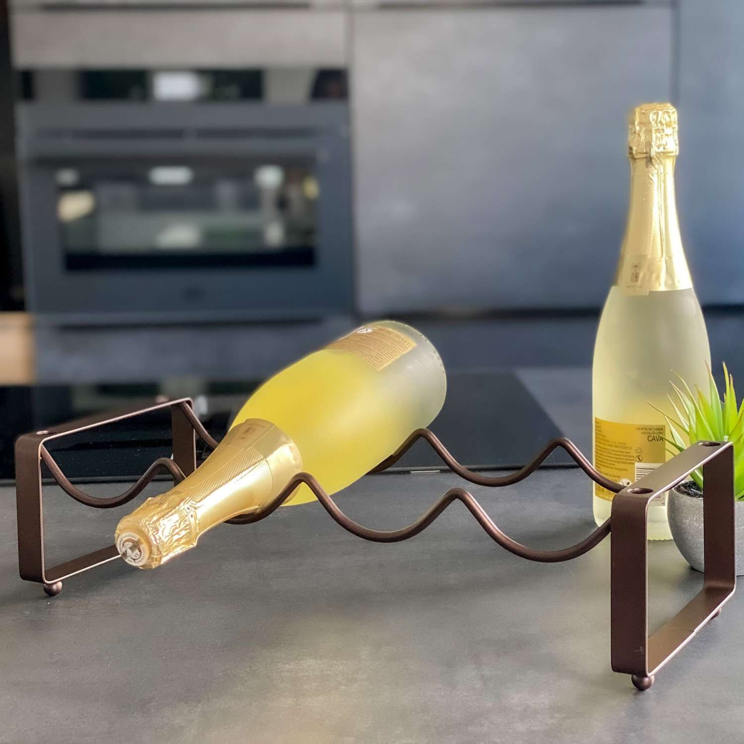 Weinflaschen in einem dekorativen Gestell auf einer Theke. Eine Flasche liegt, die andere steht.
