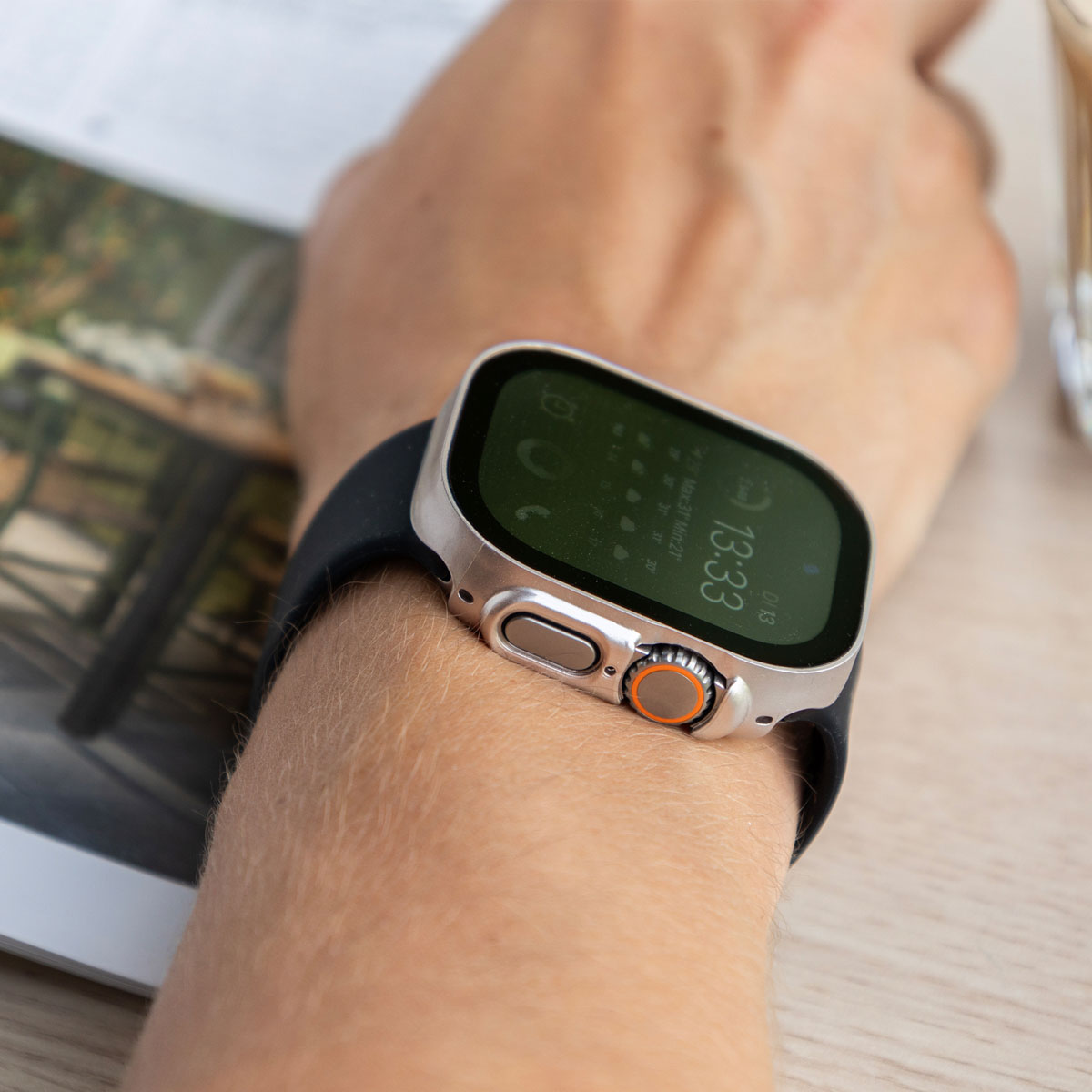 Apple Watch on a wrist, displaying time and date, with a light background.