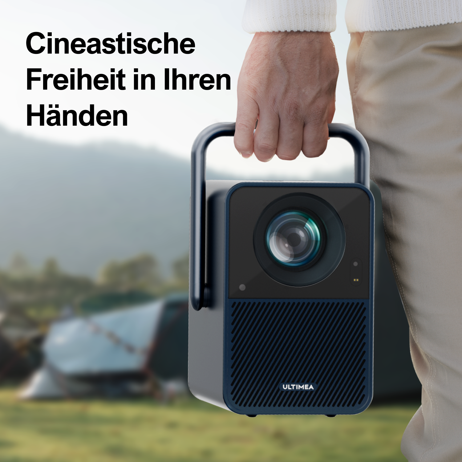 Osoba trzymająca projektor z uchwytem na tle rozmytego krajobrazu.