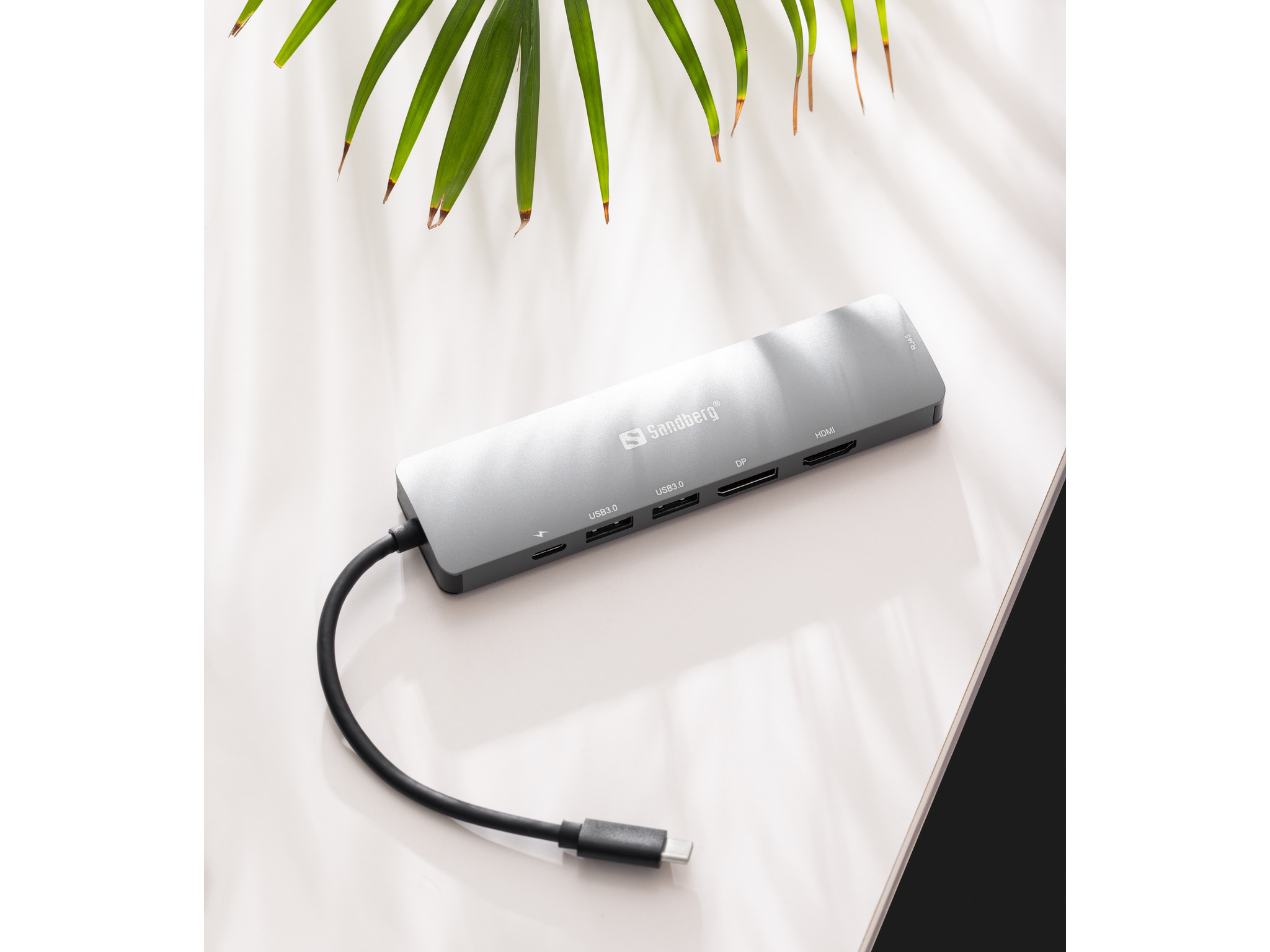 Silberner Hub mit mehreren Anschlüssen. Angeschlossen an ein schwarzes Kabel mit USB-C-Anschluss.