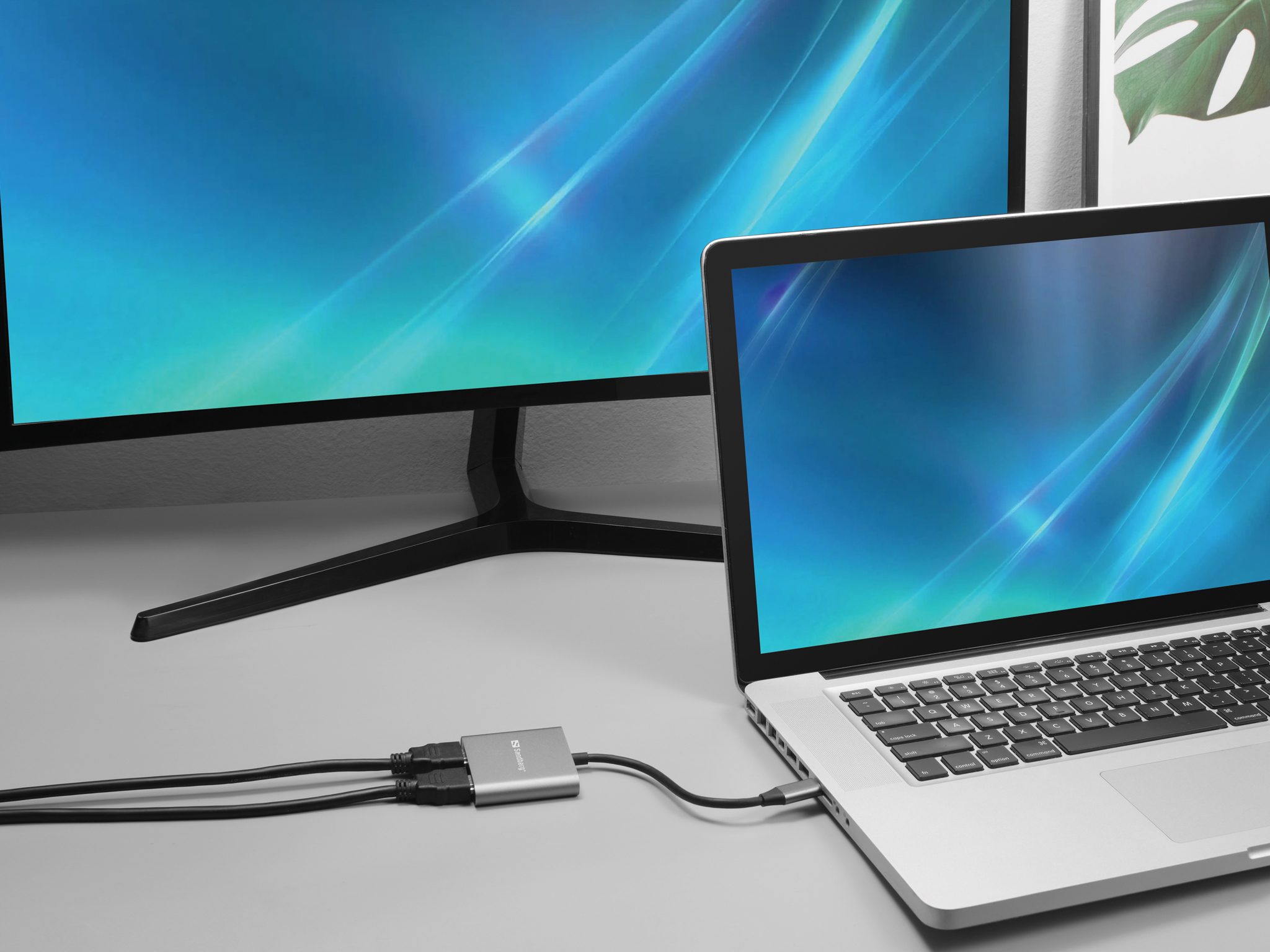 Laptop über Adapter mit zwei Monitoren verbunden. Bildschirme zeigen blauen Farbverlauf.