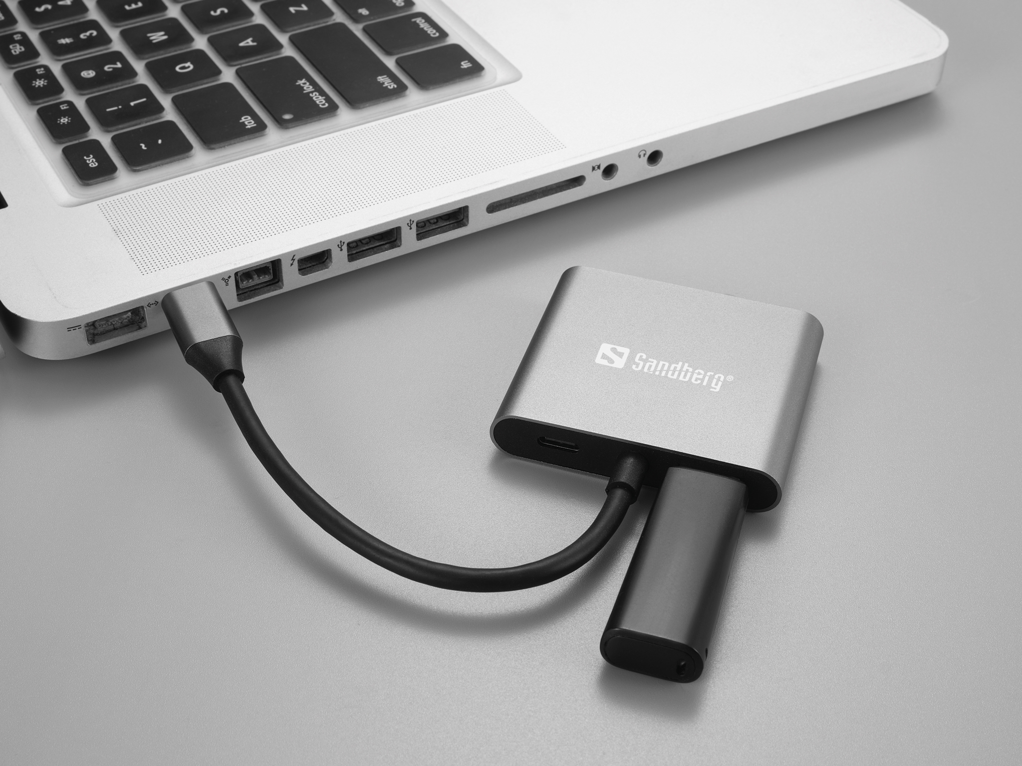 Laptop mit grauem Adapter verbunden. Grauer Hintergrund.