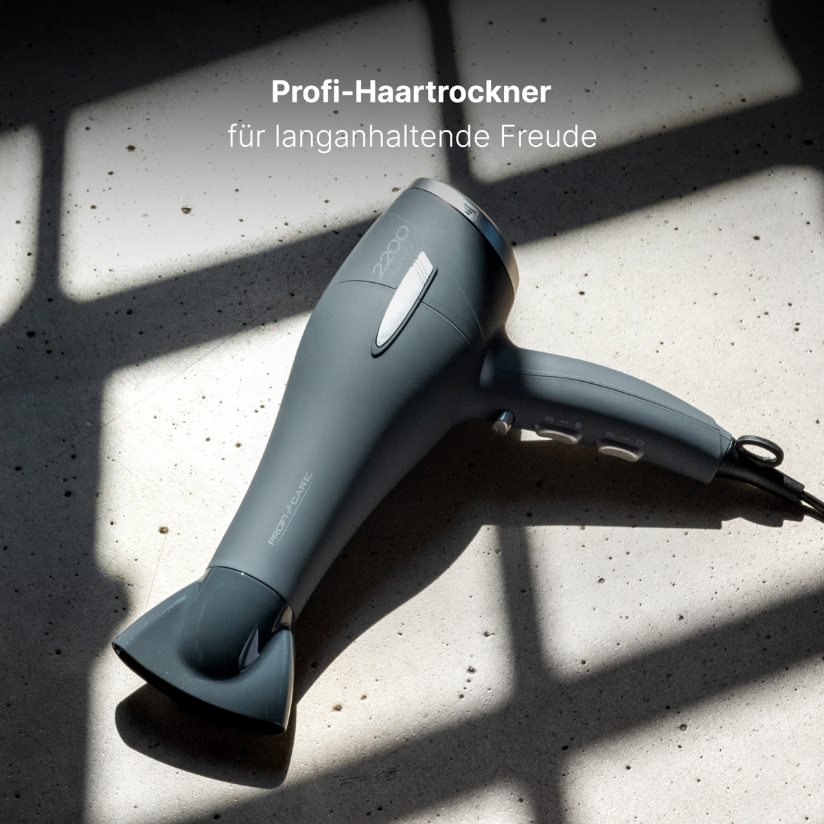 Szara suszarka do włosów z cieniem na jasnej powierzchni.