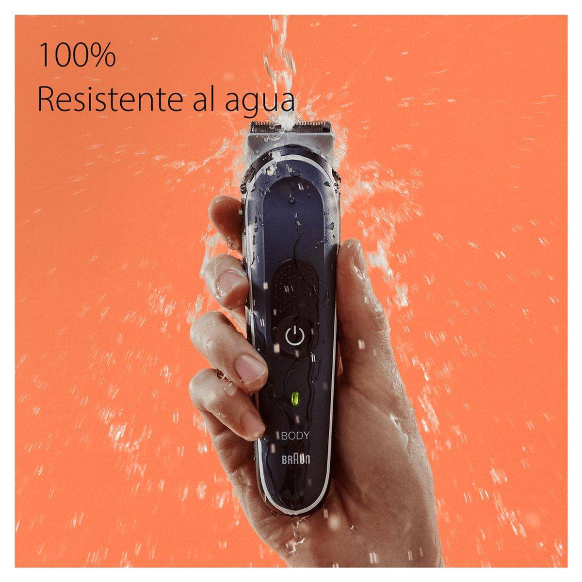 Un uomo tiene un rasoio elettrico blu scuro e nero sotto l'acqua corrente su uno sfondo arancione.