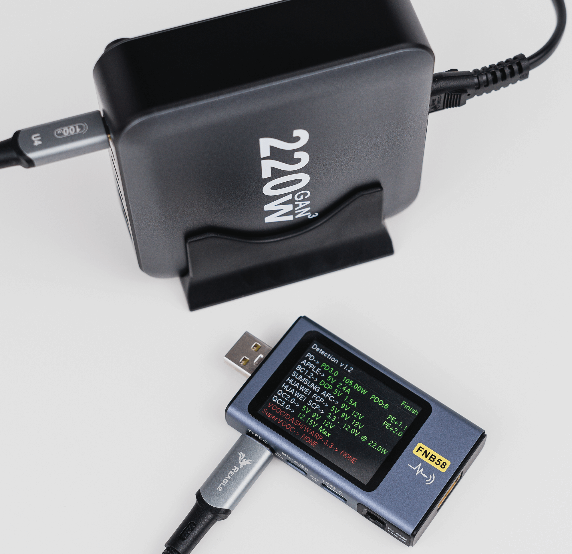 Czarny zasilacz z wpiętym kablem USB-C. Obecny jest również tester cyfrowy.