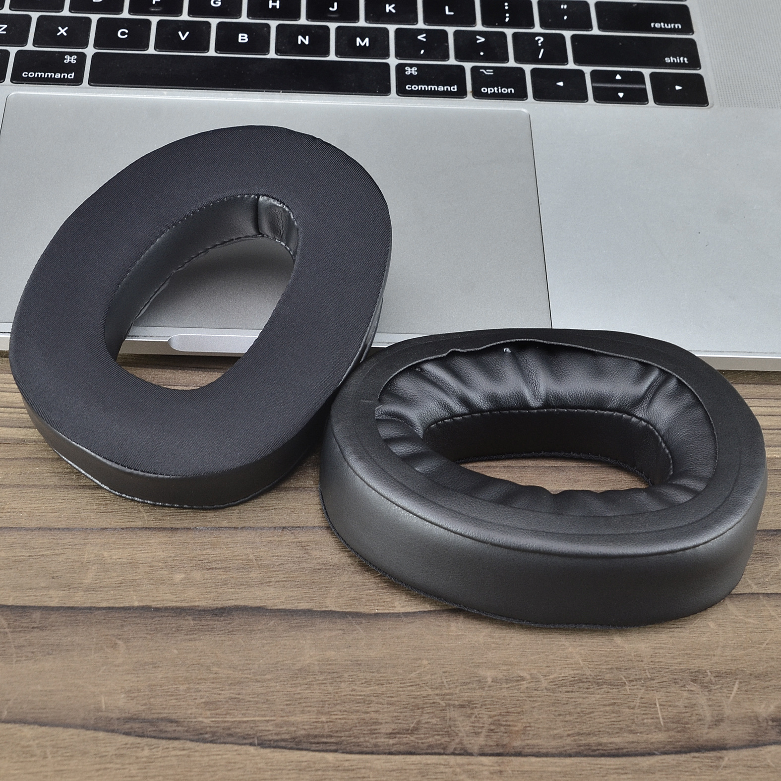 Dwie czarne nauszniki na klawiaturze laptopa. Nauszniki są owalne i wykonane ze skóry.