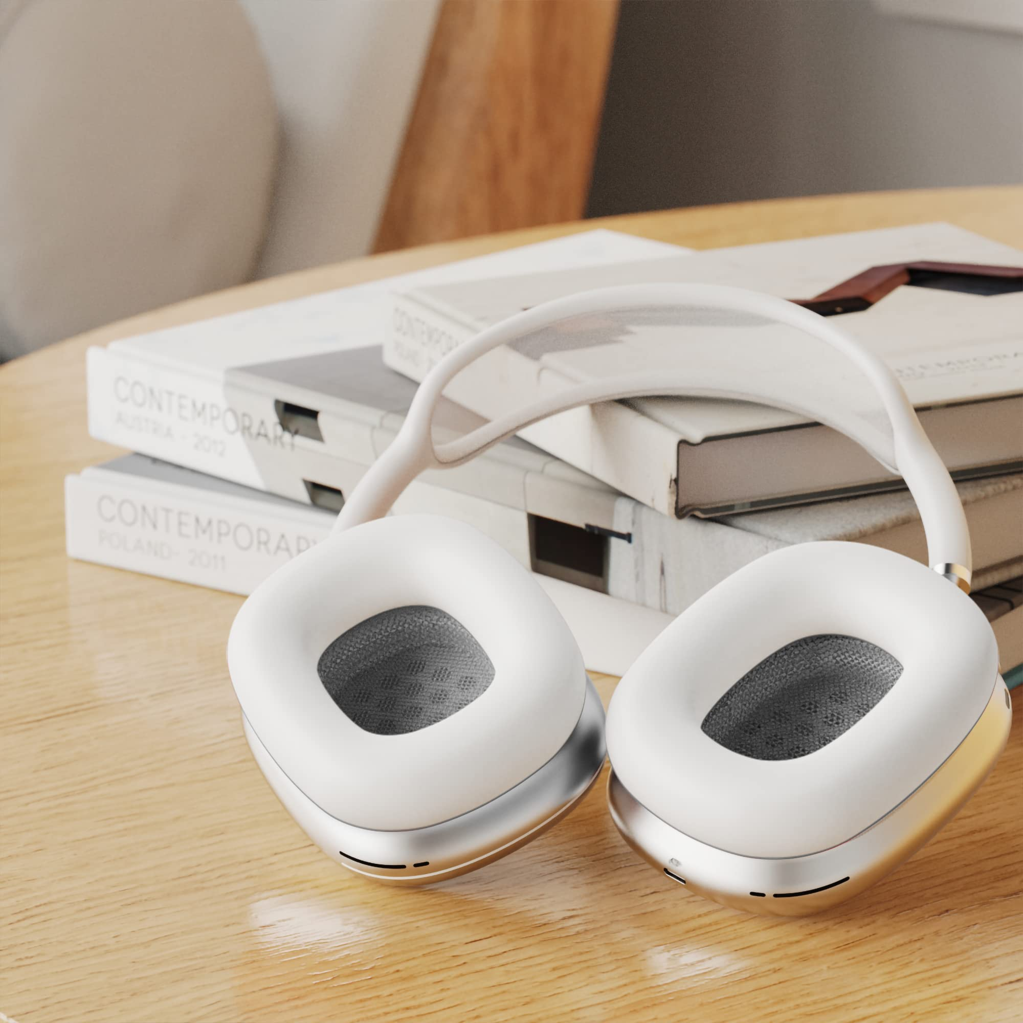 Białe i srebrne słuchawki leżą na drewnianym stole z książkami za nimi. Słuchawki znajdują się na drewnianym stole.