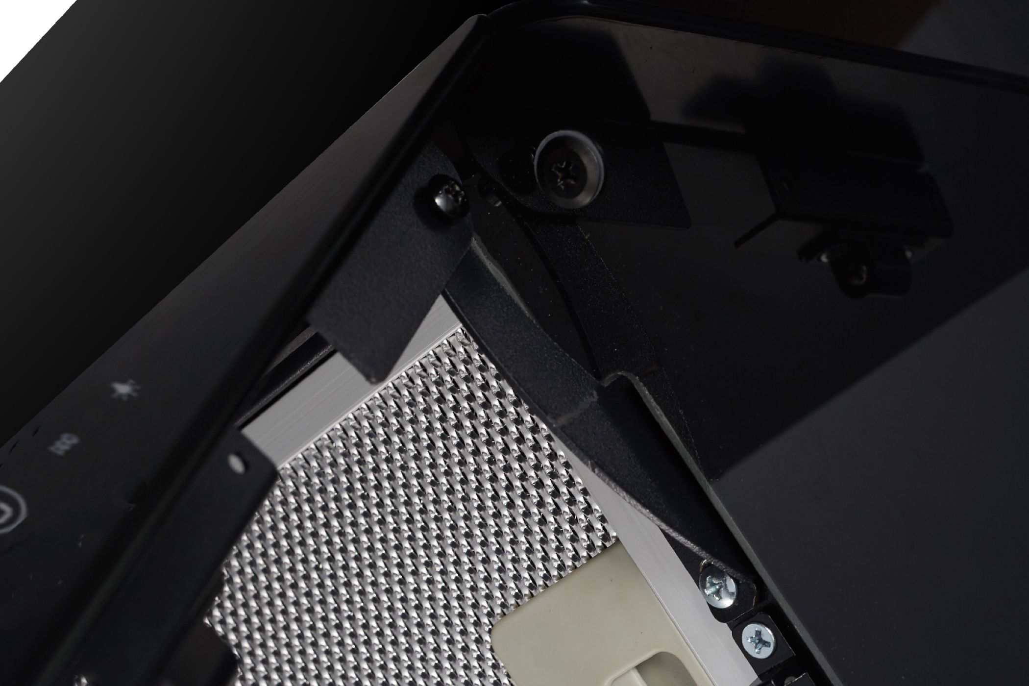 Close-up van een zwarte afzuigkap. Het heeft een metalen gaasfilter en een glazen paneel.
