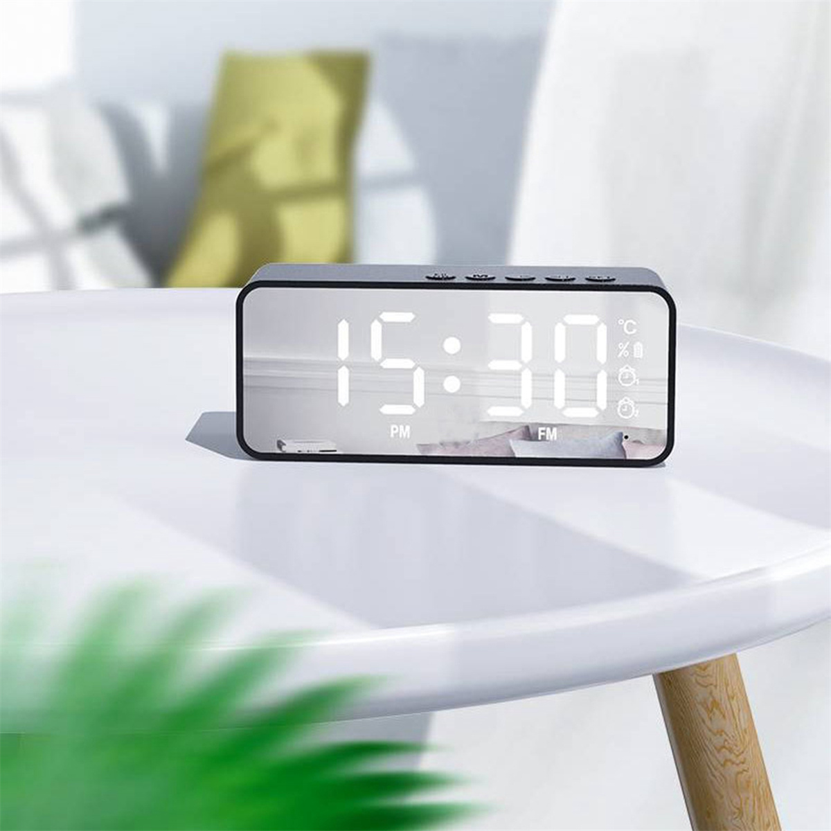 Ein digitaler Wecker. Er ist schwarz mit einem verspiegelten Display, das Zeit, Temperatur und andere Symbole anzeigt.