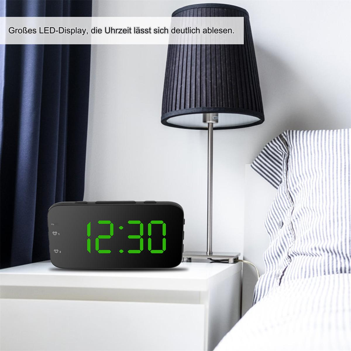 Schwarzer digitaler Wecker, der 12:30 mit grünen Zahlen anzeigt. Auf einem weißen Nachttisch.