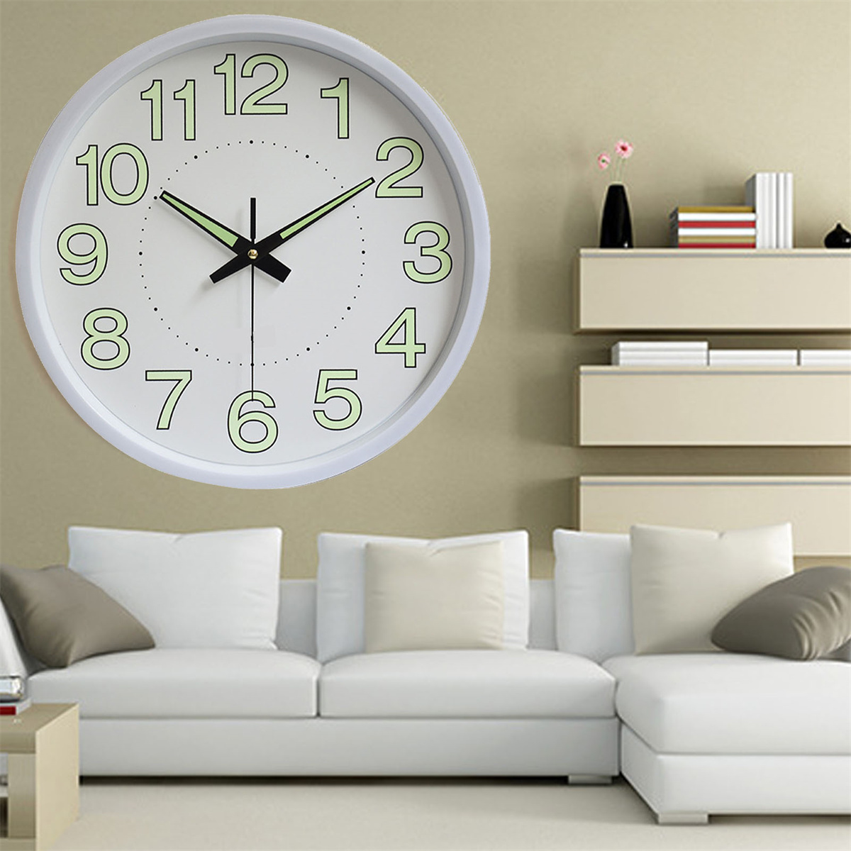 Weiße Wanduhr mit grünen Zahlen und schwarzen Zeigern, an einer beigen Wand.