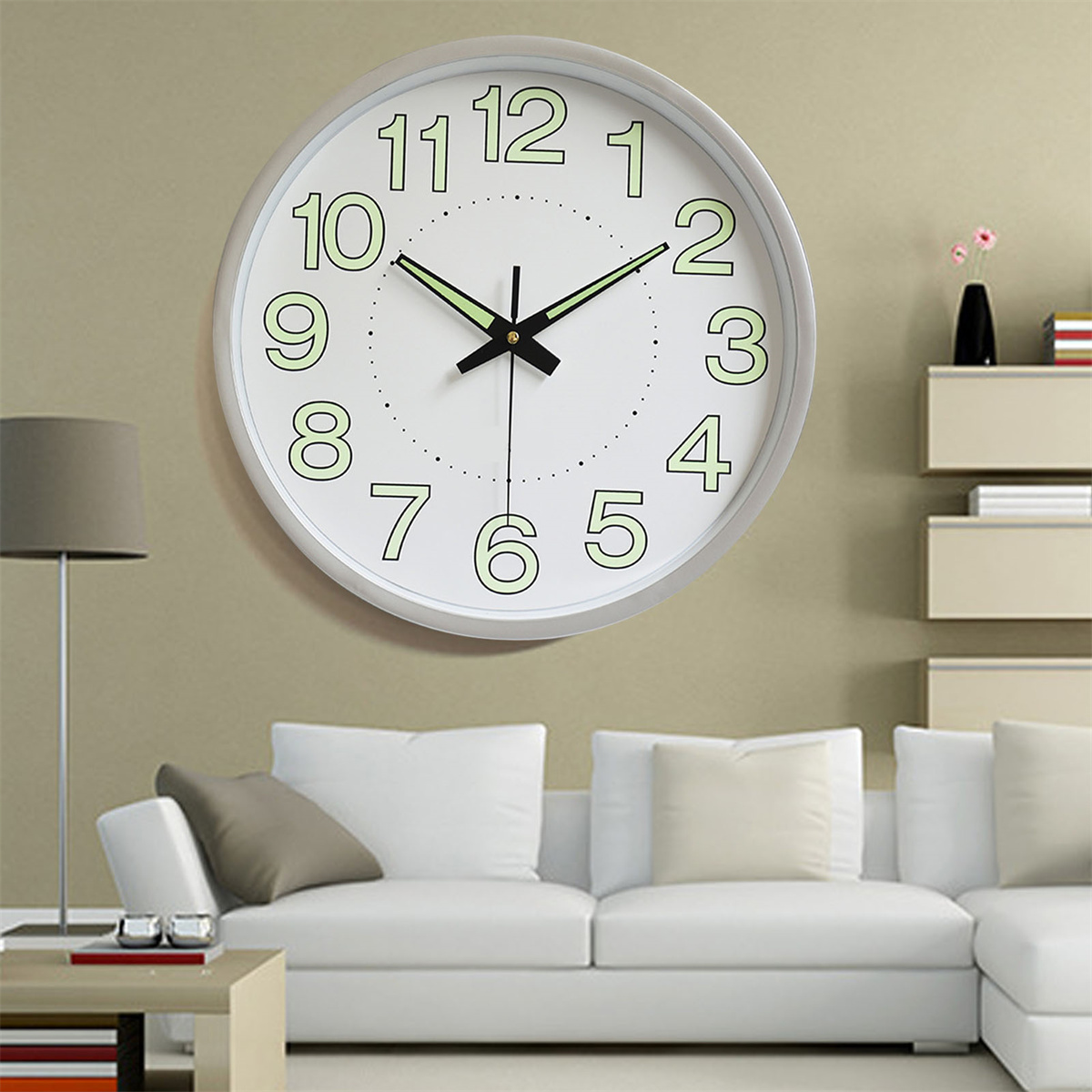 Runde Wanduhr mit grünen Zahlen und Zeigern an einer beigen Wand und weißem Sofa.