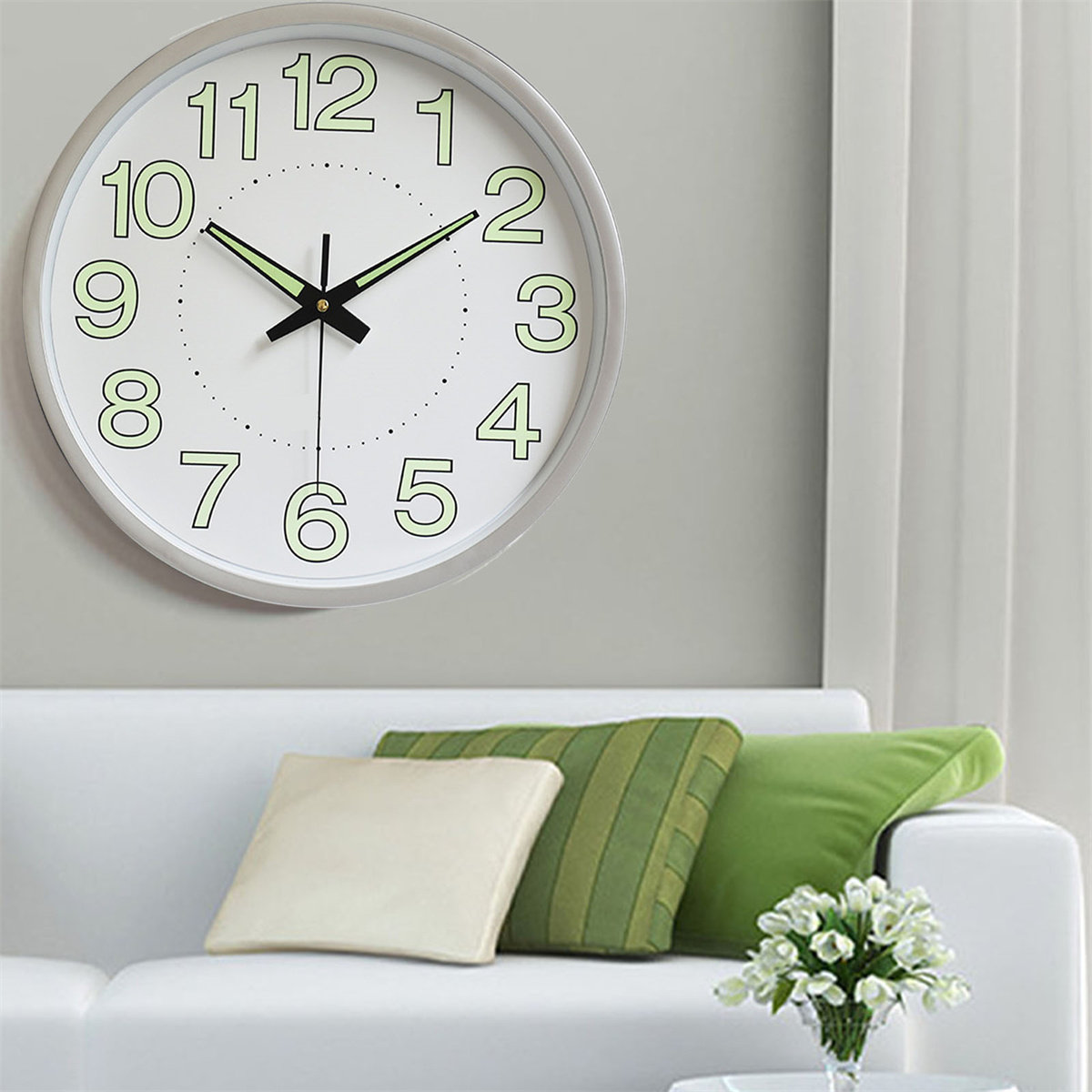 Leuchtende Uhr an grauer Wand, mit Sofa und Kissen.