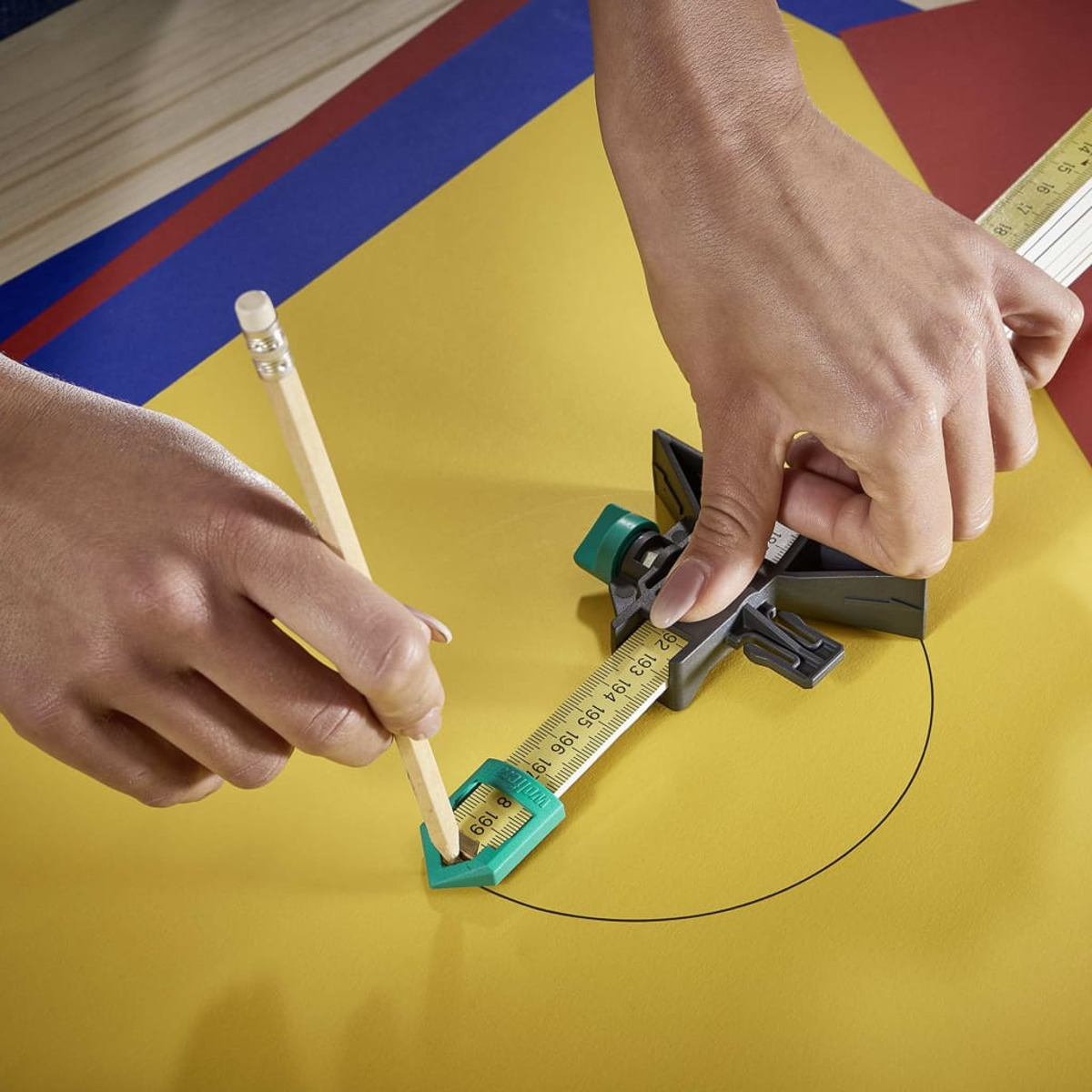 Hände, die mit Bleistift und Messwerkzeug auf gelber Oberfläche einen Kreis zeichnen.