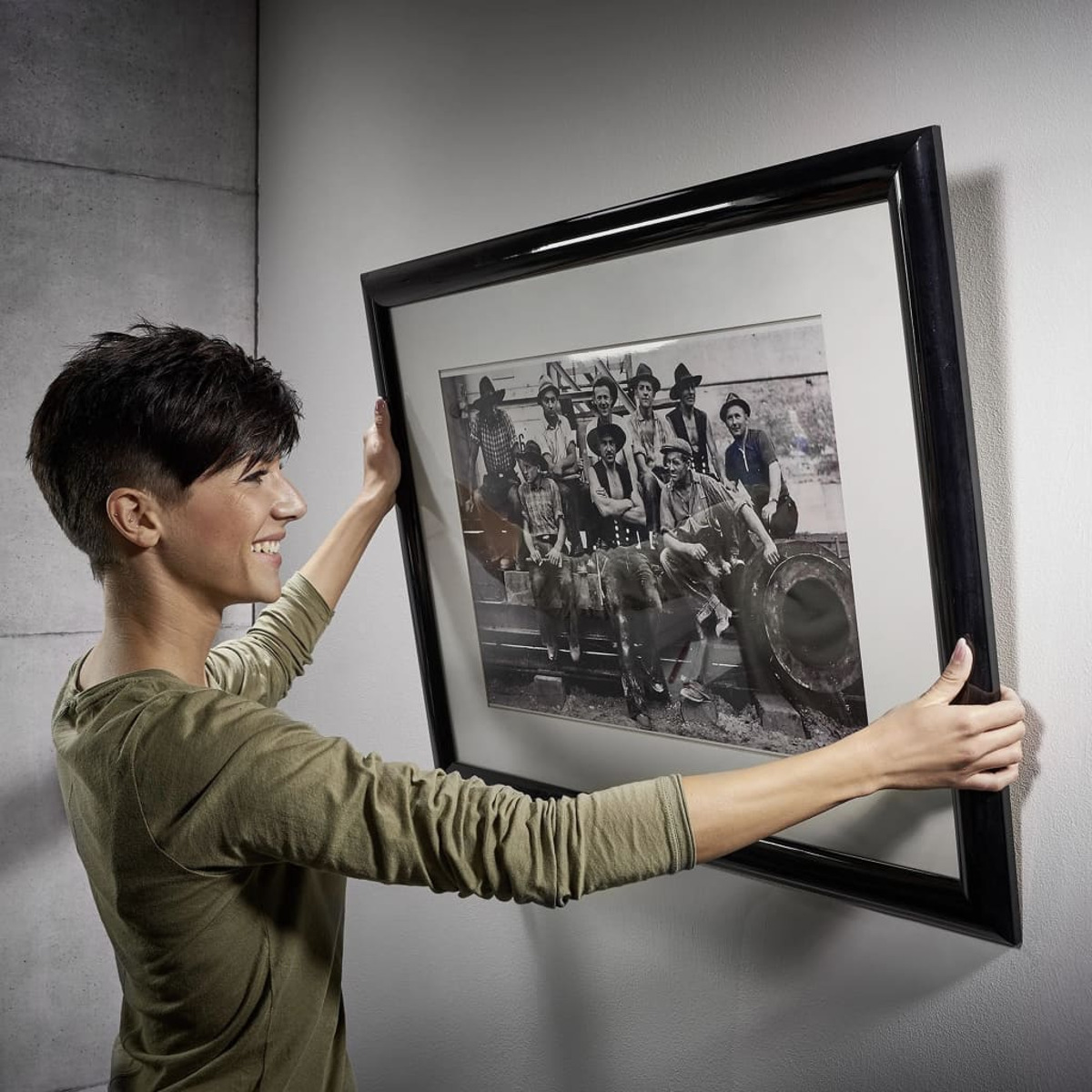 Frau hält ein gerahmtes Schwarz-Weiß-Foto von Leuten, lächelnd.