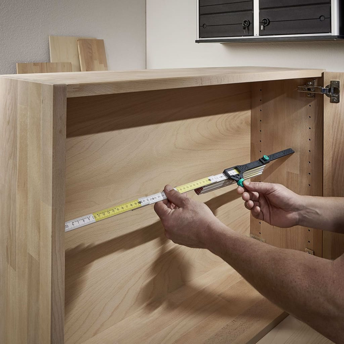 Person misst die Innenseite eines Holzschranks mit Lineal und Messwerkzeug.