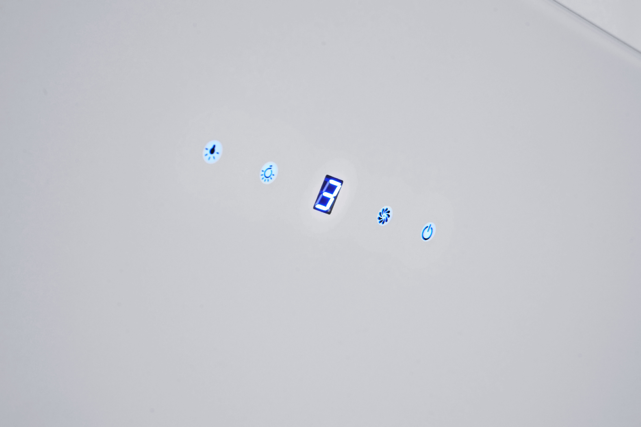 Primo piano di un pannello di controllo bianco con indicatori luminosi blu.