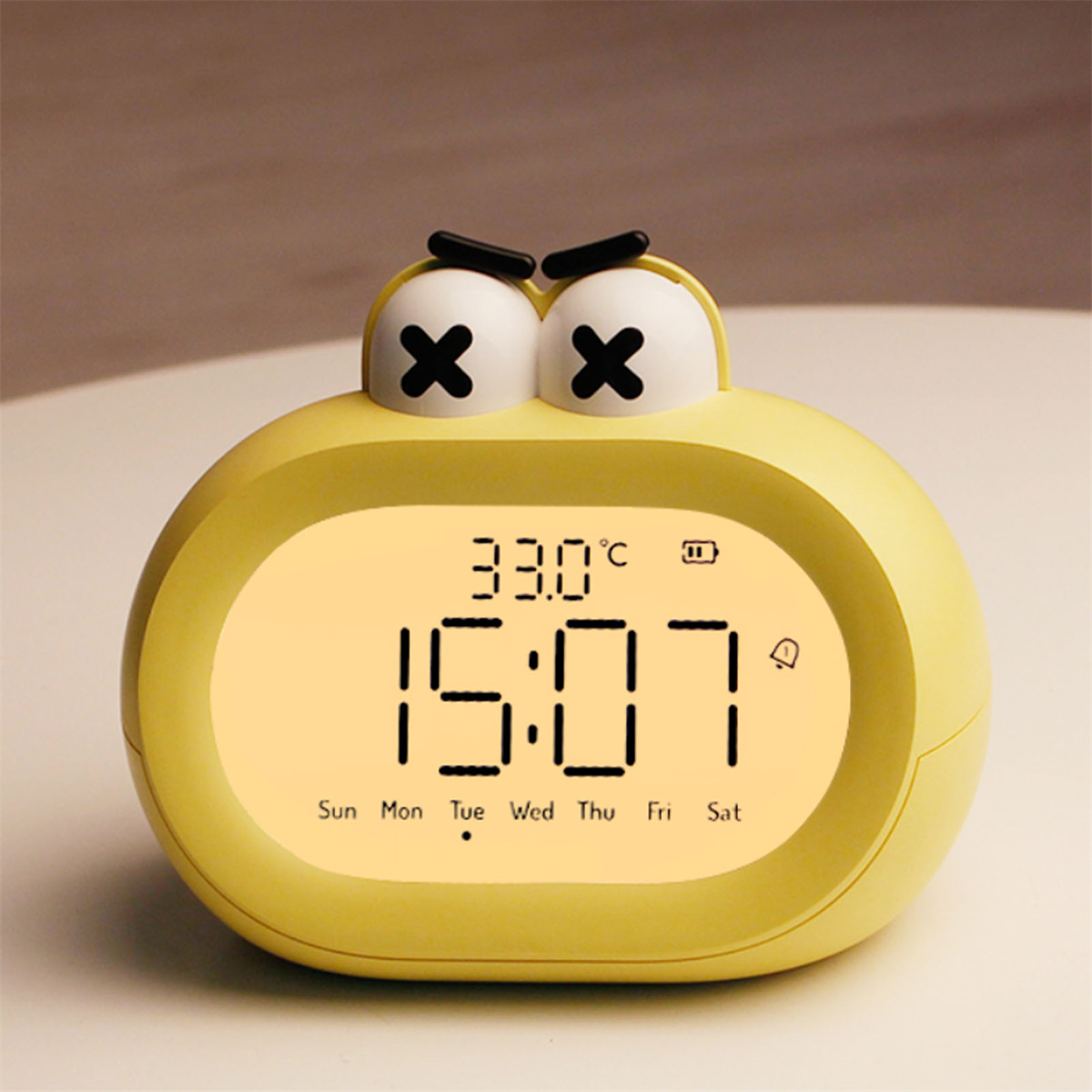Gelber froschförmiger Wecker mit digitaler Anzeige von Zeit und Temperatur.